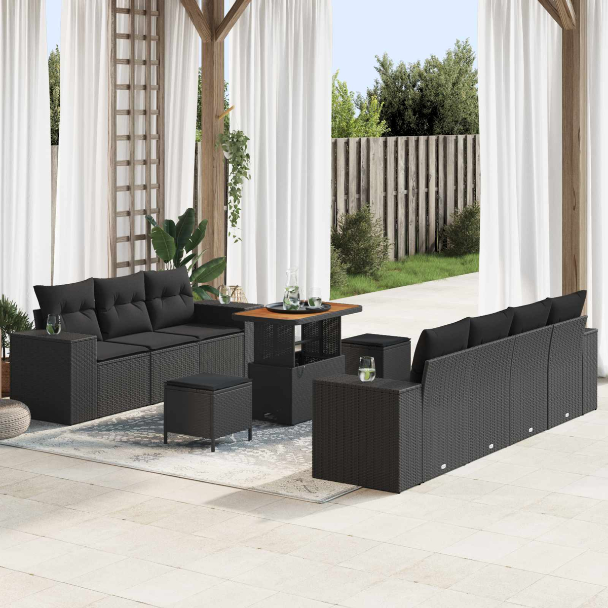 Dunkelgraue Rattan-Gartenmöbel mit schwarzen Kissen auf einer Terrasse.
