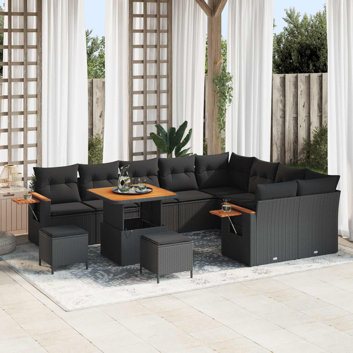 Ein schwarzes modulares Outdoor-Sofa mit Holztisch und Hockern auf einer Terrasse.
