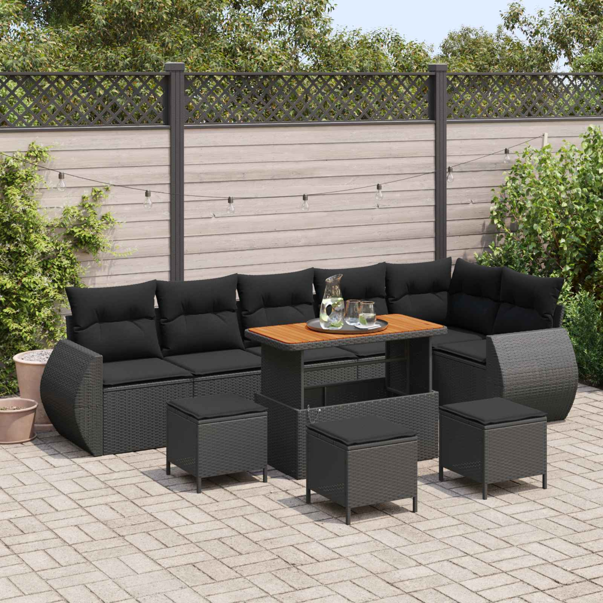 Un conjunto de muebles de exterior oscuros con cojines y otomanas en un patio pavimentado.