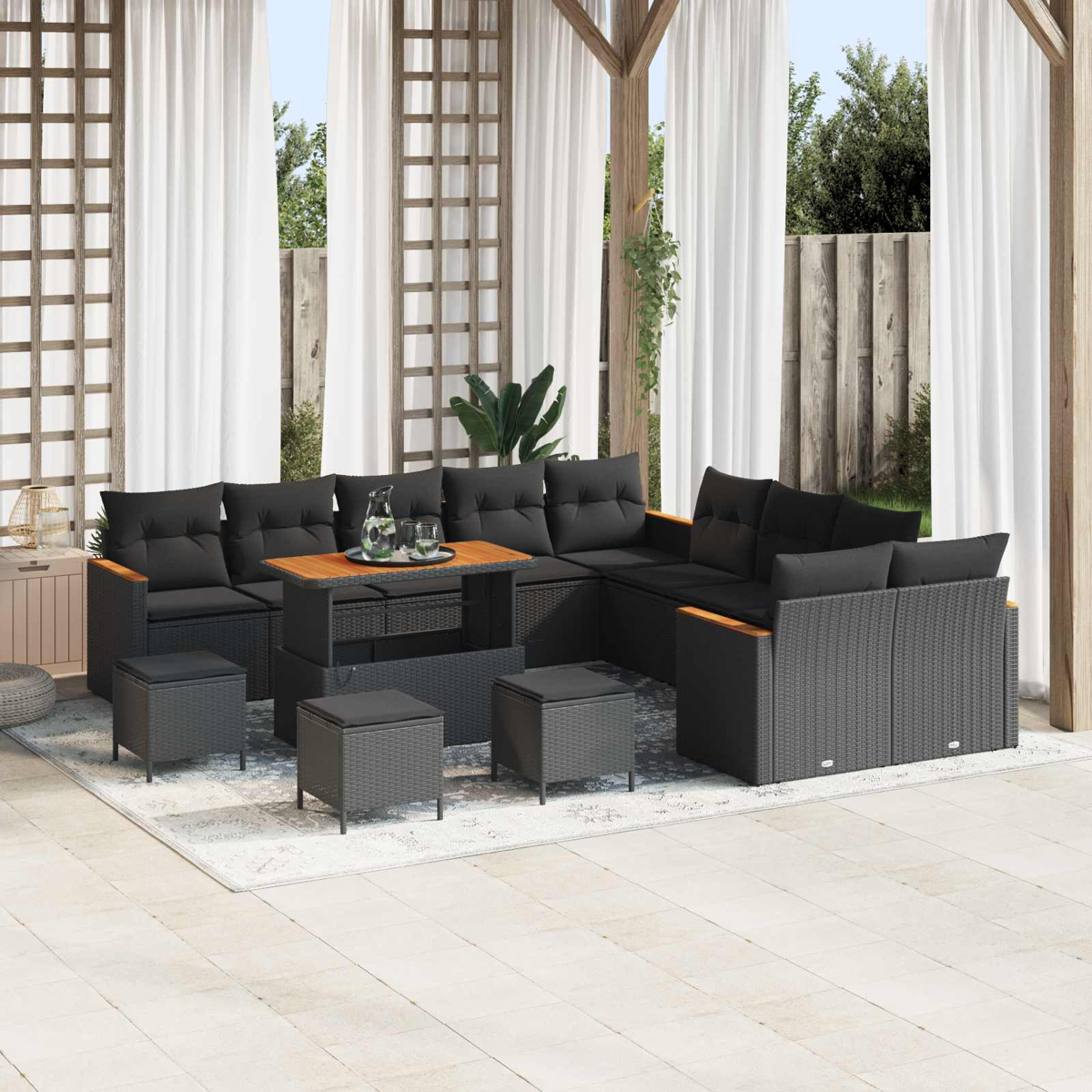 Draußen-Lounge mit schwarzen Kissen, Holztisch und Hockern.