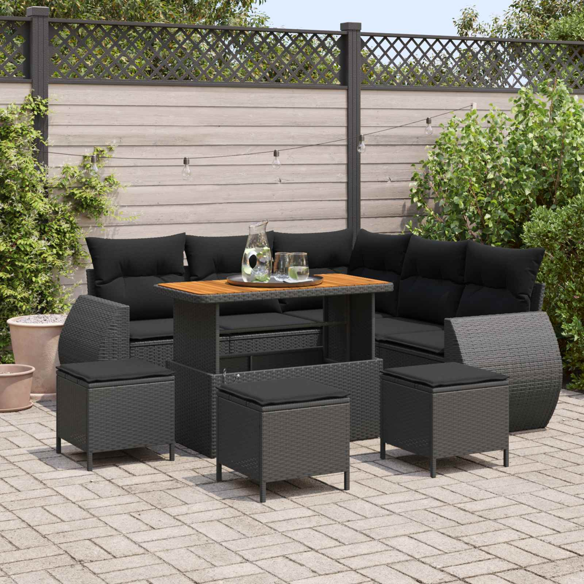 Ein Rattan-Gartenmöbel-Set mit schwarzer Polsterung und einem Holztisch.