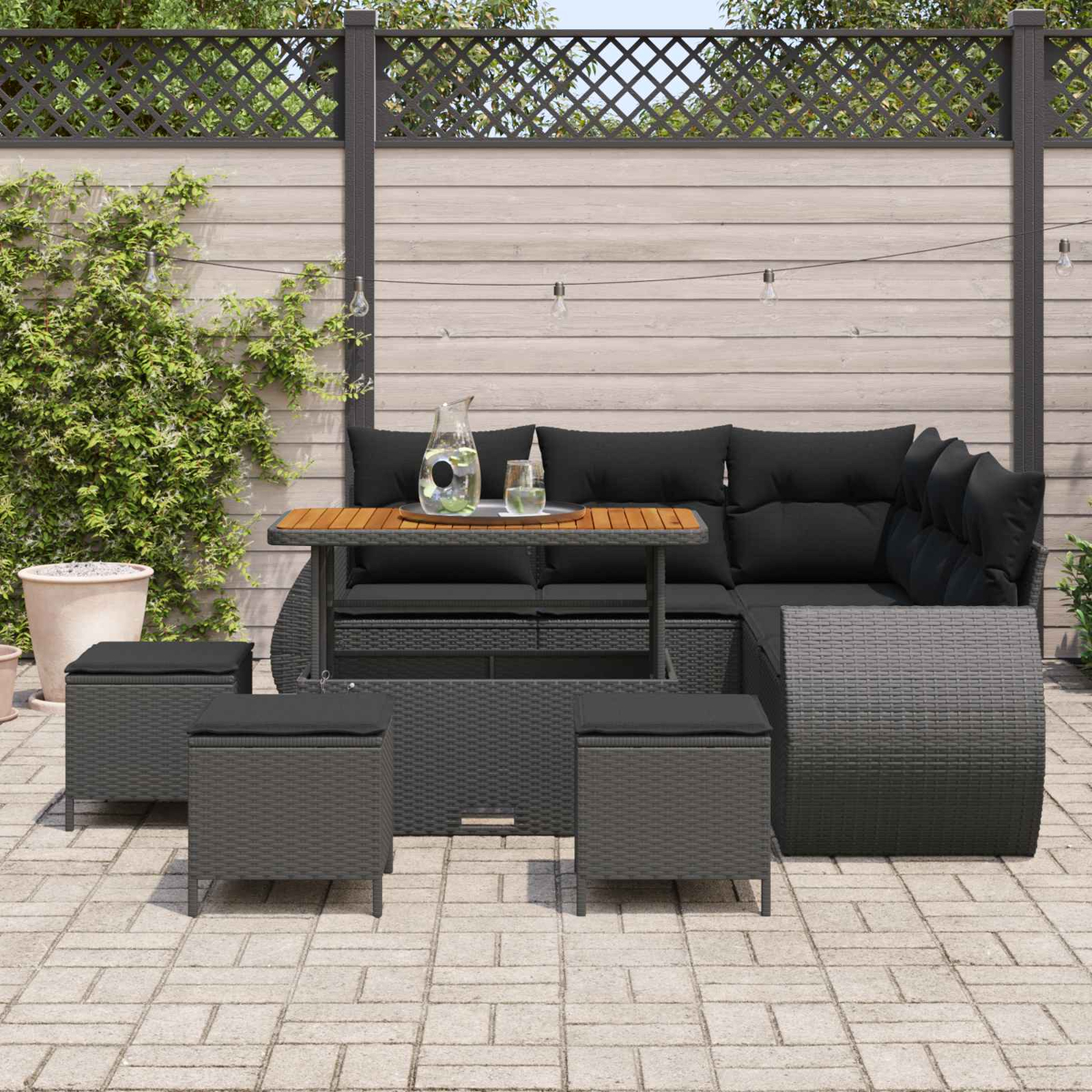 Dunkelgraue Lounge-Garnitur mit Hockern und verstellbarem Tisch auf einer Terrasse.