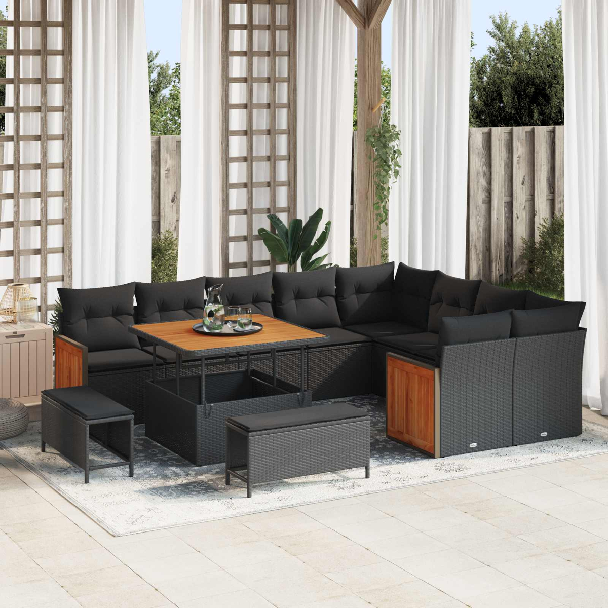 Ein moderner Outdoor-Loungebereich mit schwarzem Rattan-Sofa, Holztisch und Hockern.