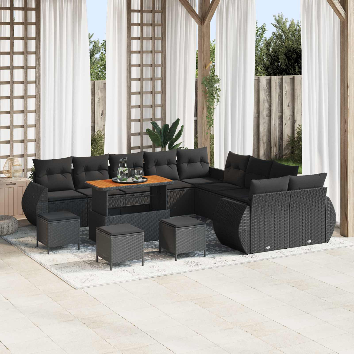 Ein schwarzes Rattan-Lounge-Set mit Kissen und einem Couchtisch auf einer Terrasse.