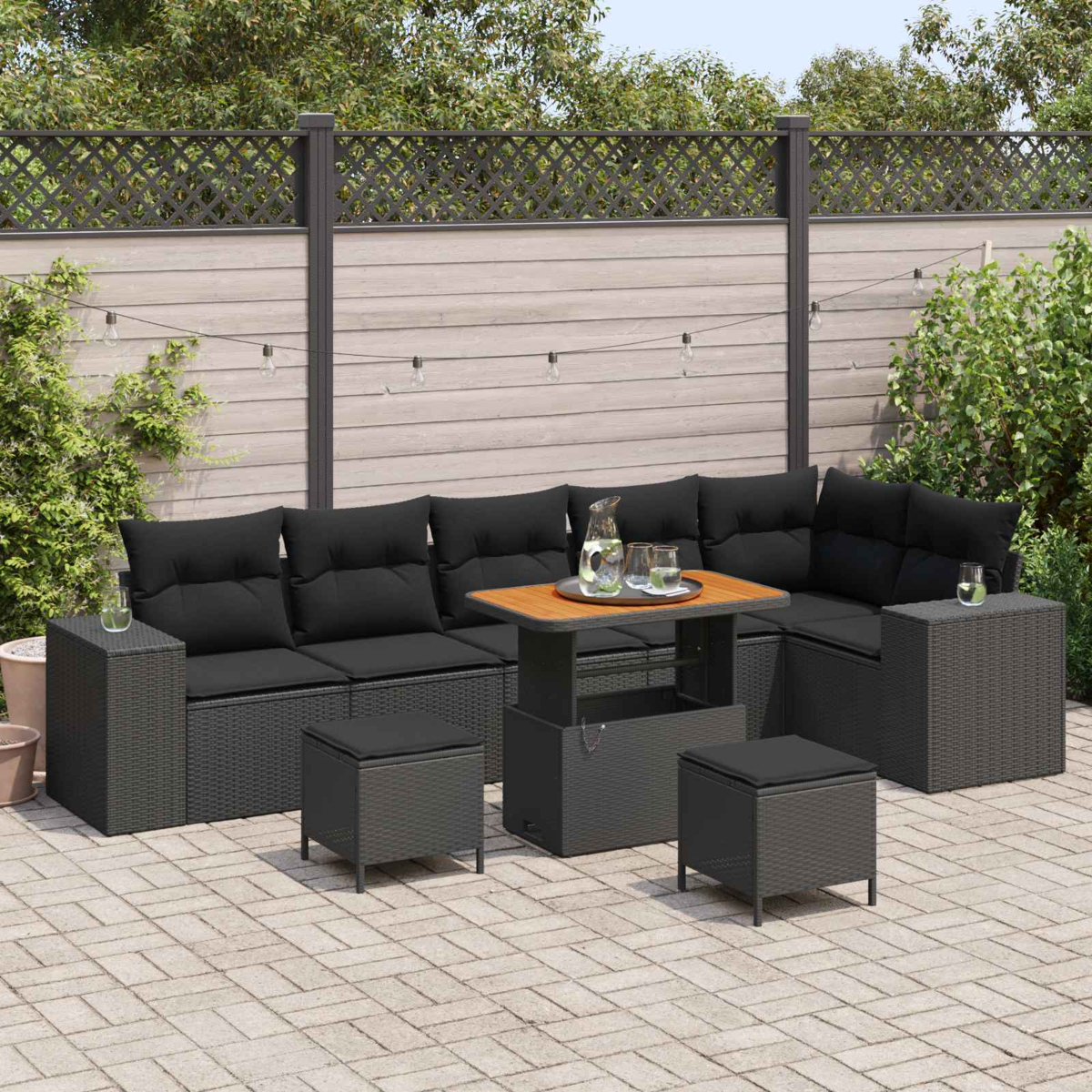 Outdoor-Sektionssofa mit schwarzen Kissen, einem Tisch mit Hubtisch und Hockern auf einer Terrasse.