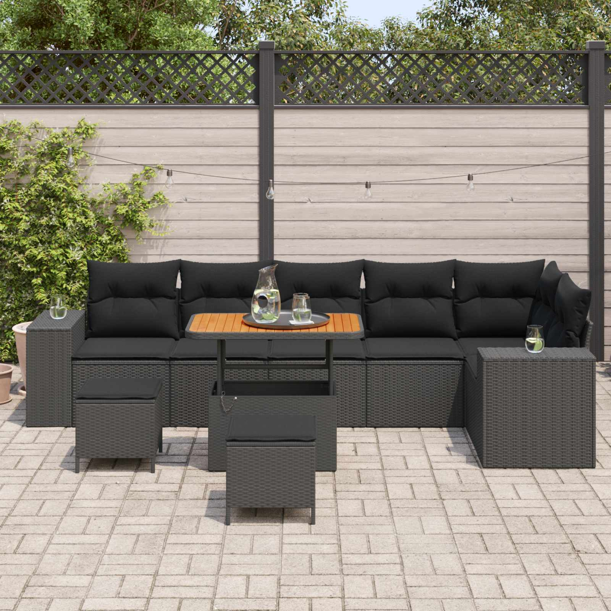 Dunkelgraue Gartenmöbel mit schwarzen Kissen, Holztisch und Gläsern auf der Terrasse.