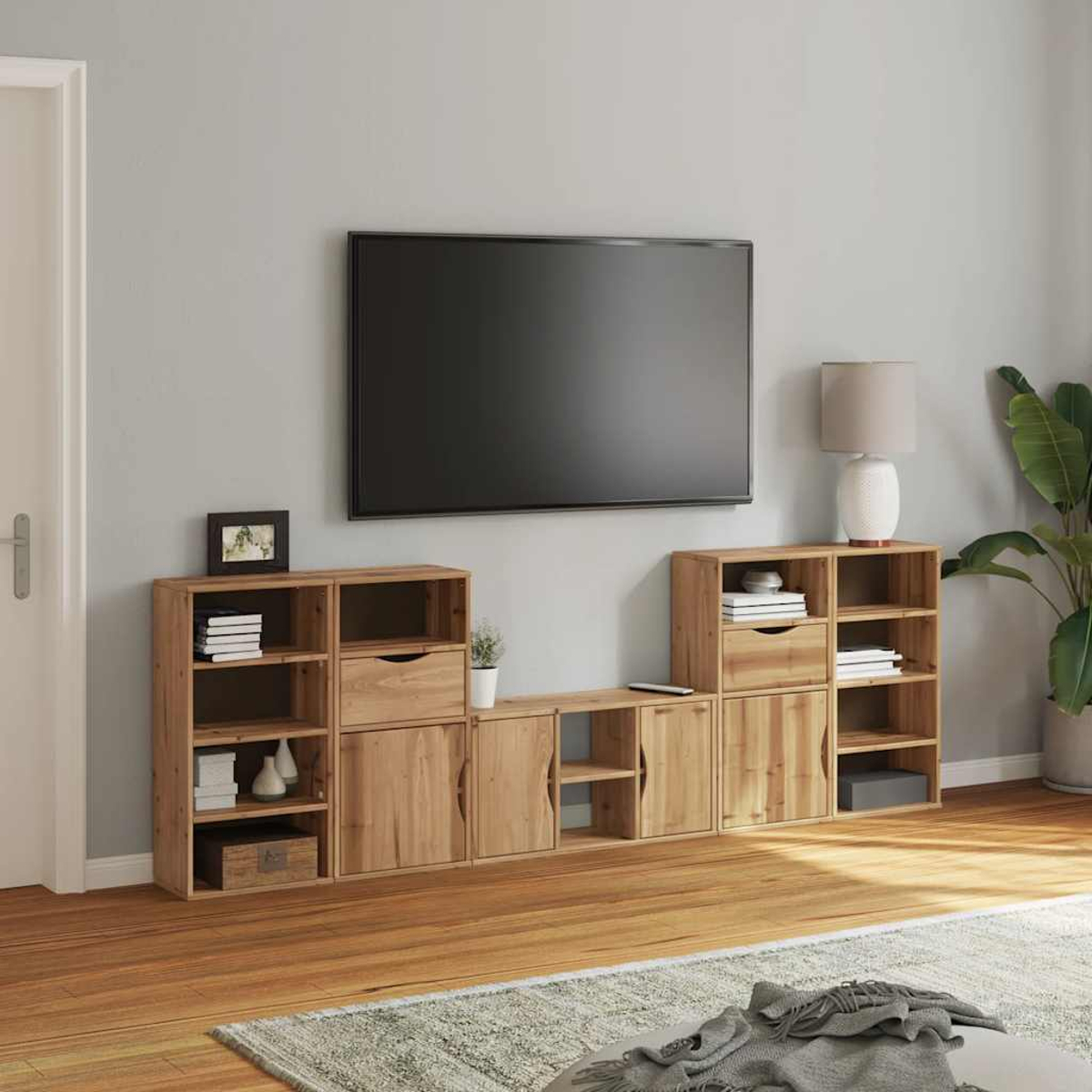 Ein Wohnzimmer mit einem großen Flachbildfernseher über Holzschränken und Regalen.