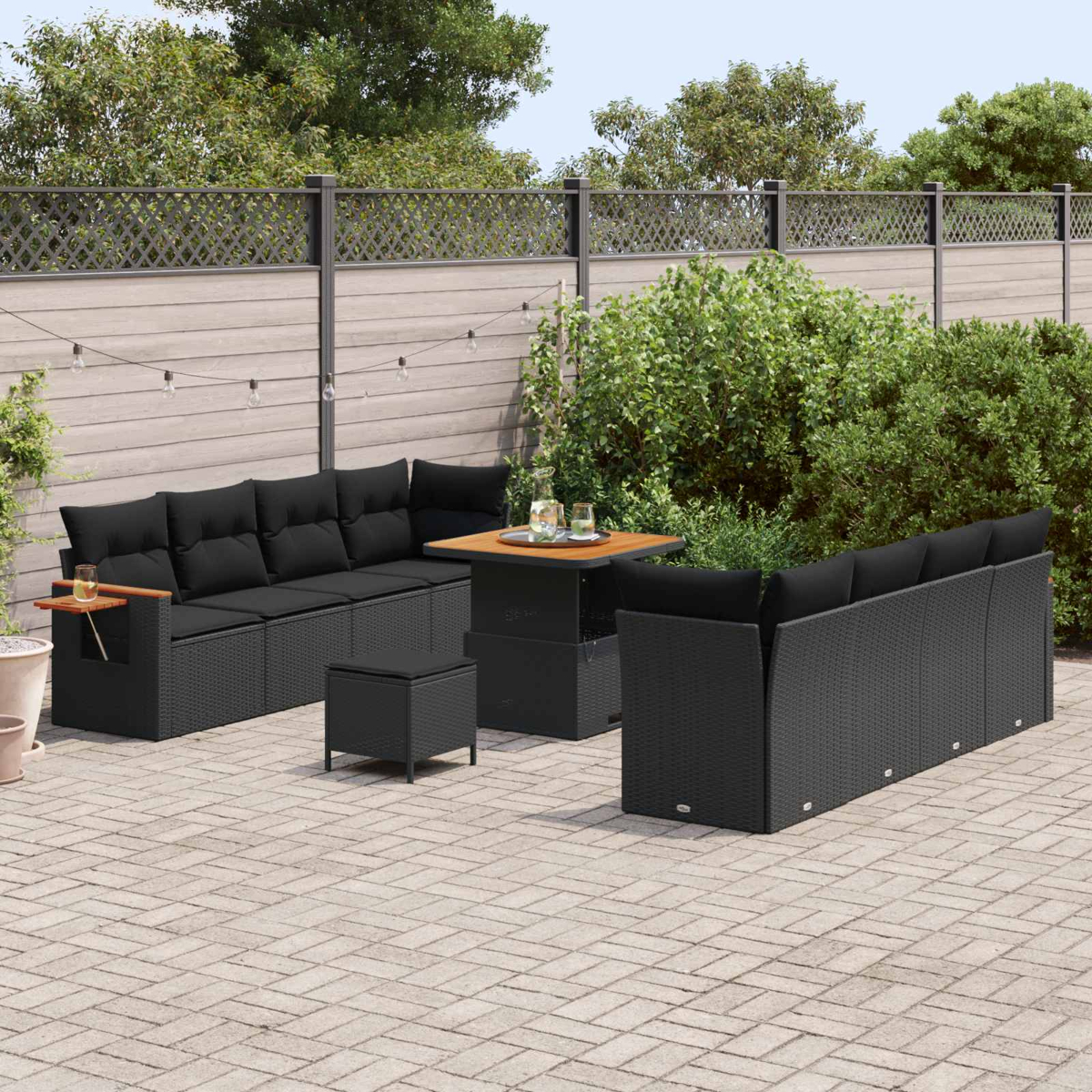 Mobili da salotto in rattan nero con cuscini su un patio pavimentato.