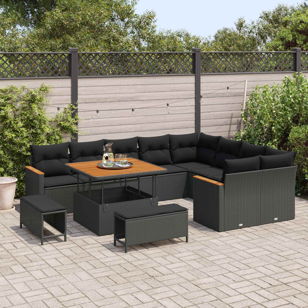 Un conjunto de muebles de exterior oscuros con cojines y mesa se asienta en un patio pavimentado.
