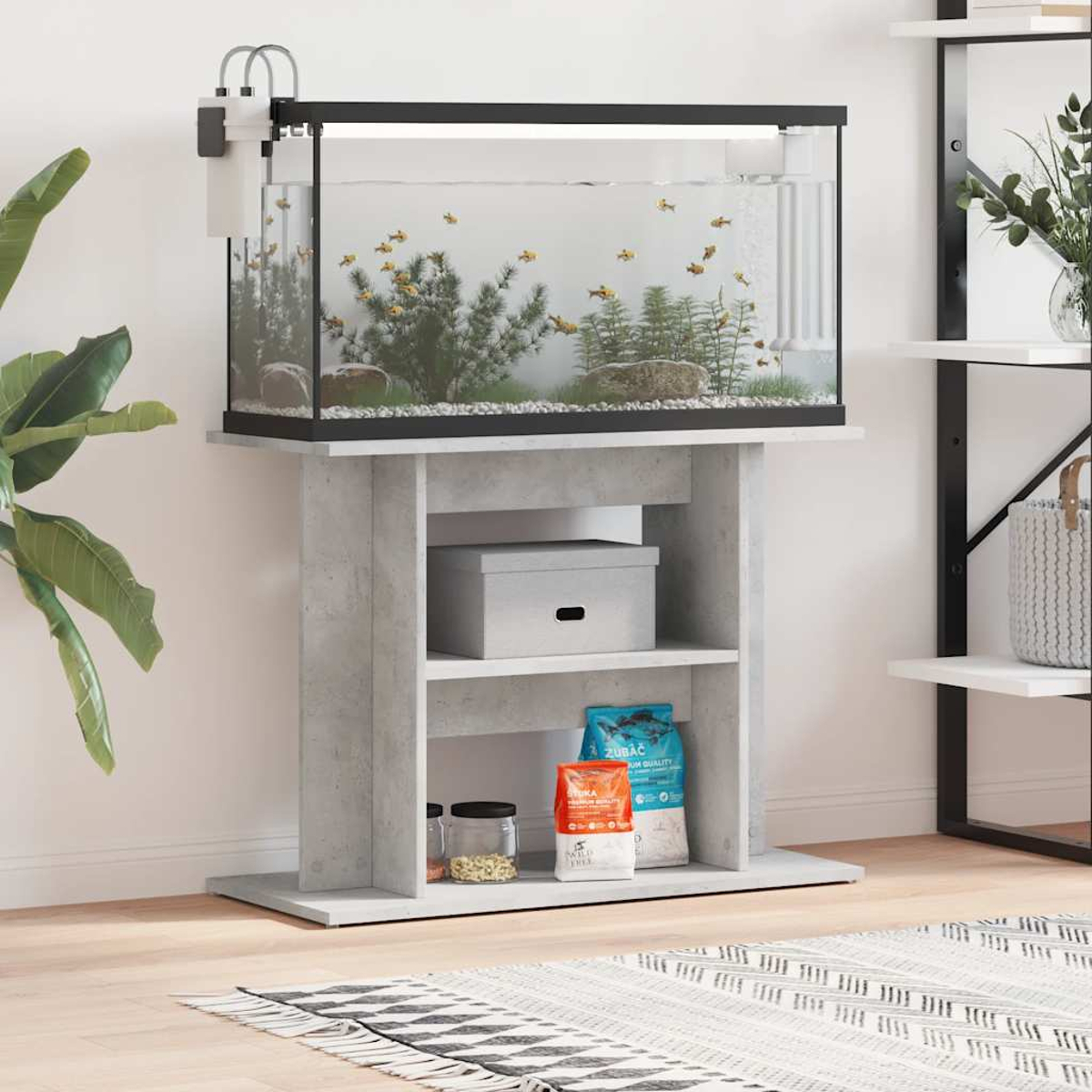 Ein Aquarium mit gelben Fischen steht auf einem Betonständer mit Regalen.