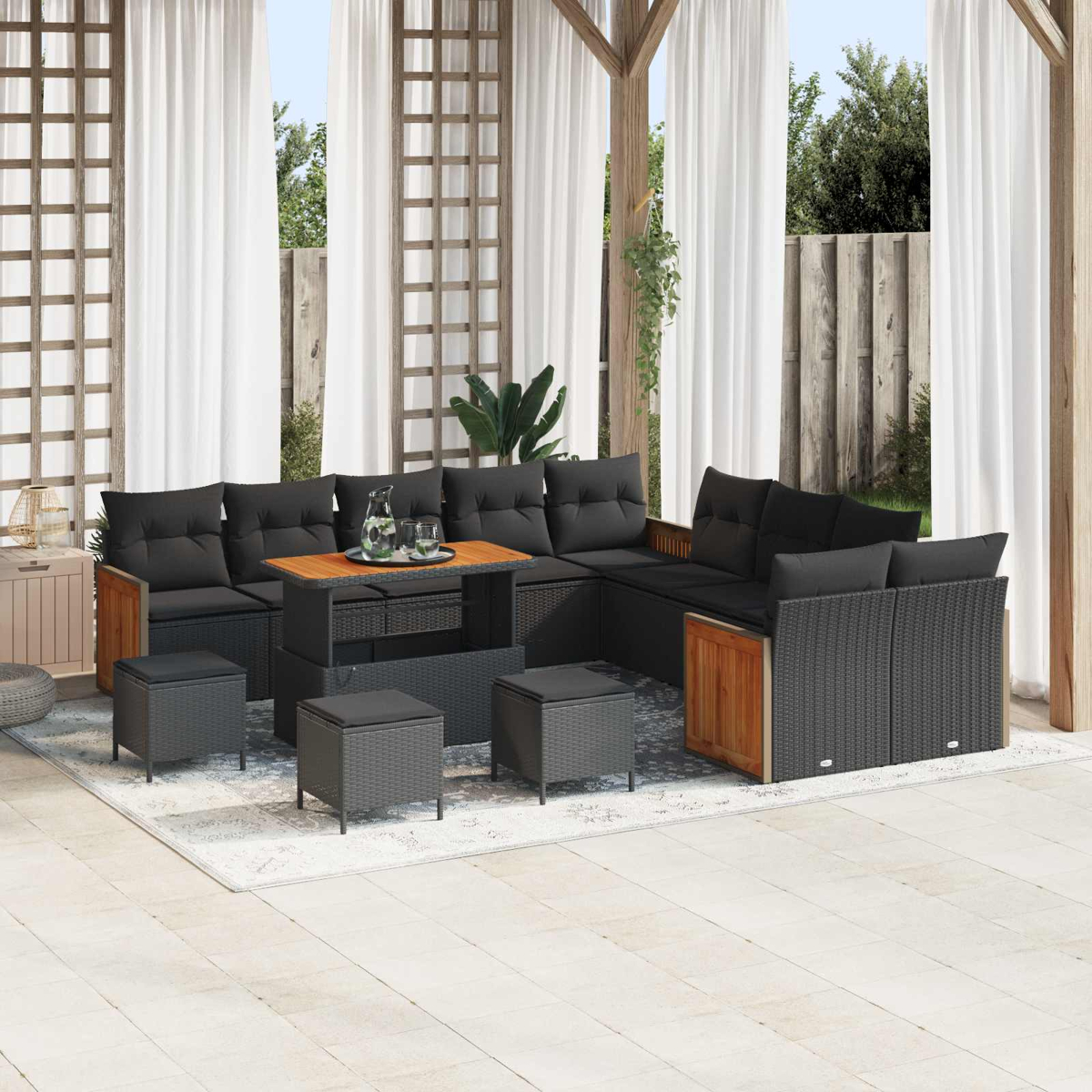Draußen-Lounge-Set mit schwarzen Polstern, Holztisch und Hockern auf einer Terrasse.