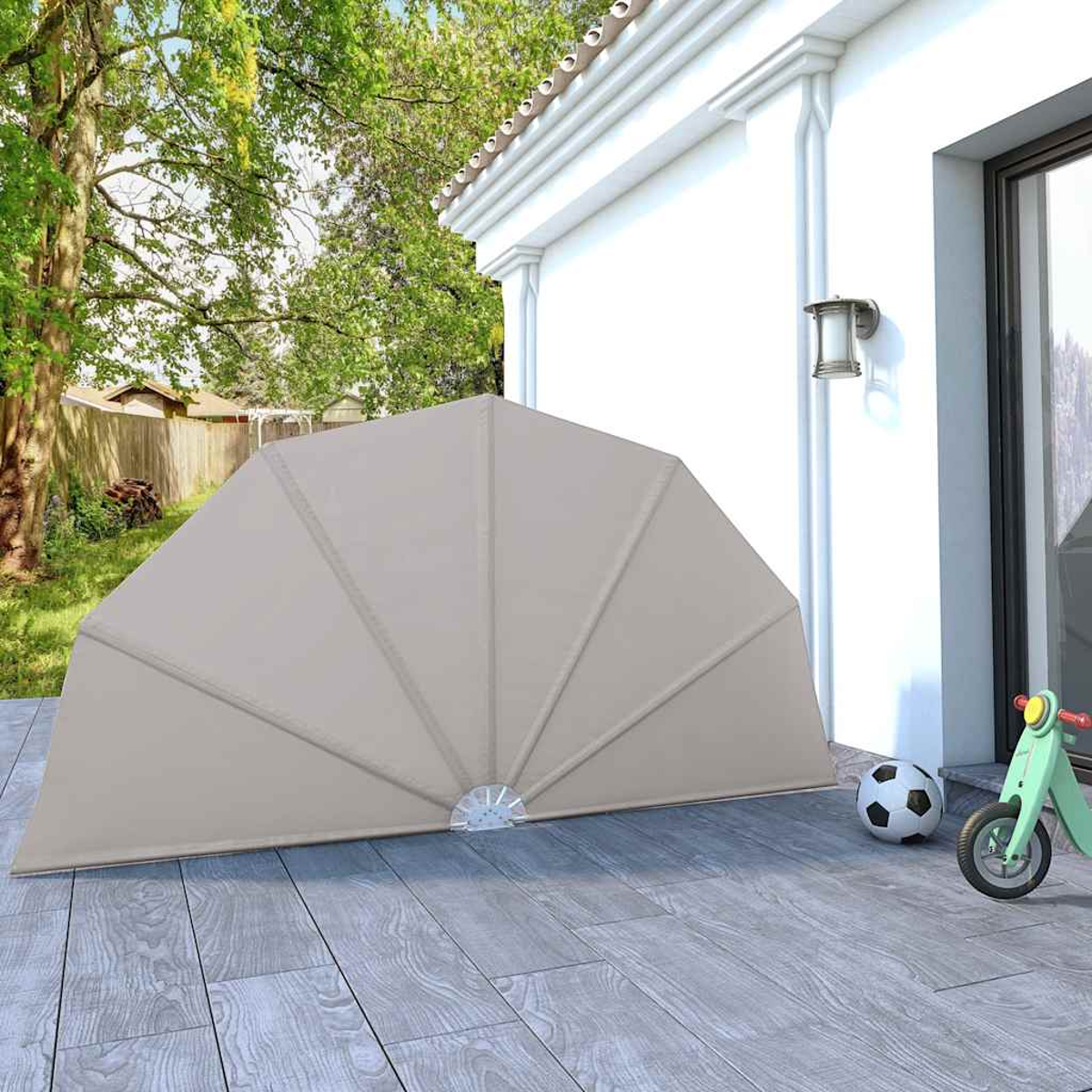 Ein beiger fächerförmiger Sonnenschutz steht auf einer Holzterrasse mit Fußball und Roller.