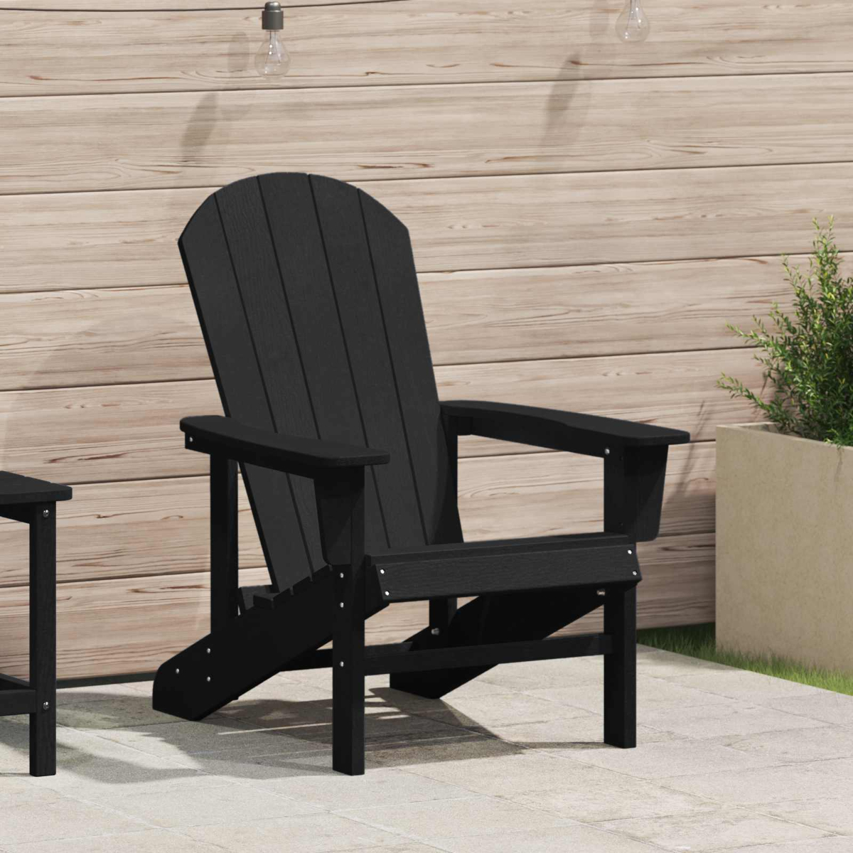 Schwarzer Adirondack-Stuhl auf einer Terrasse vor einer Holzwand.
