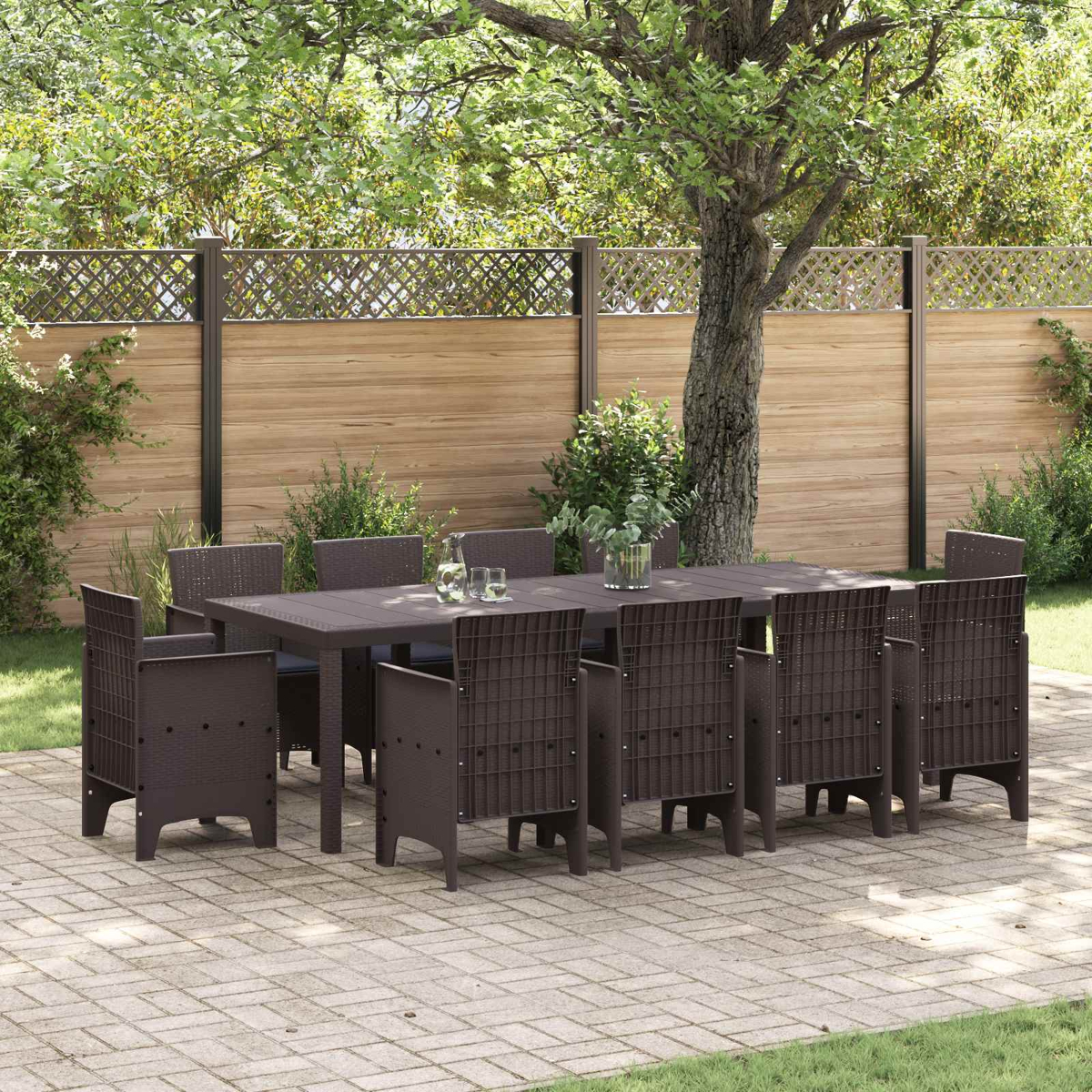 Ein braunes Gartenmöbelset mit Tisch und Stühlen auf einer Steinterrasse, umgeben von Grün.