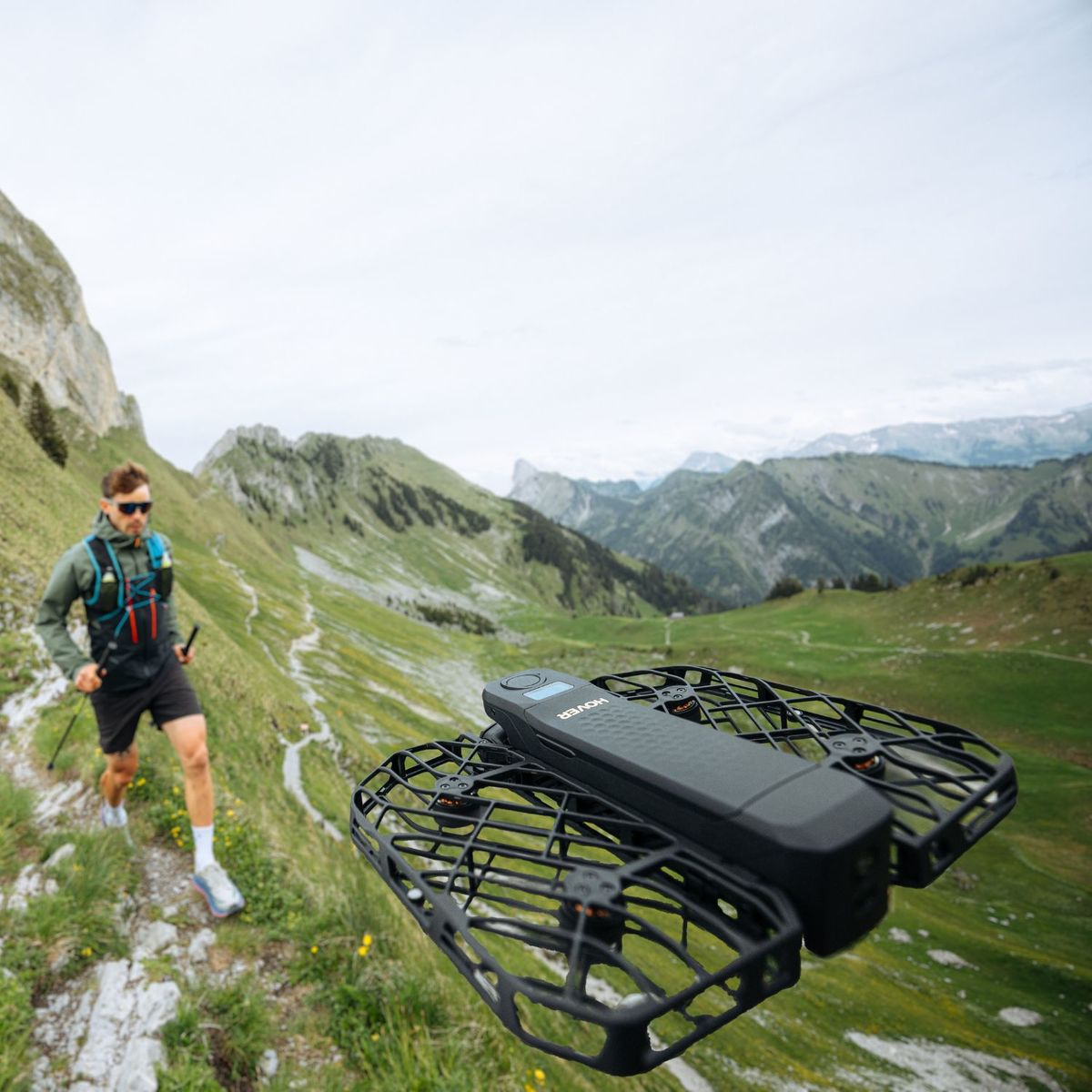 Mężczyzna biegnie ścieżką górską, dron leci przed nim.