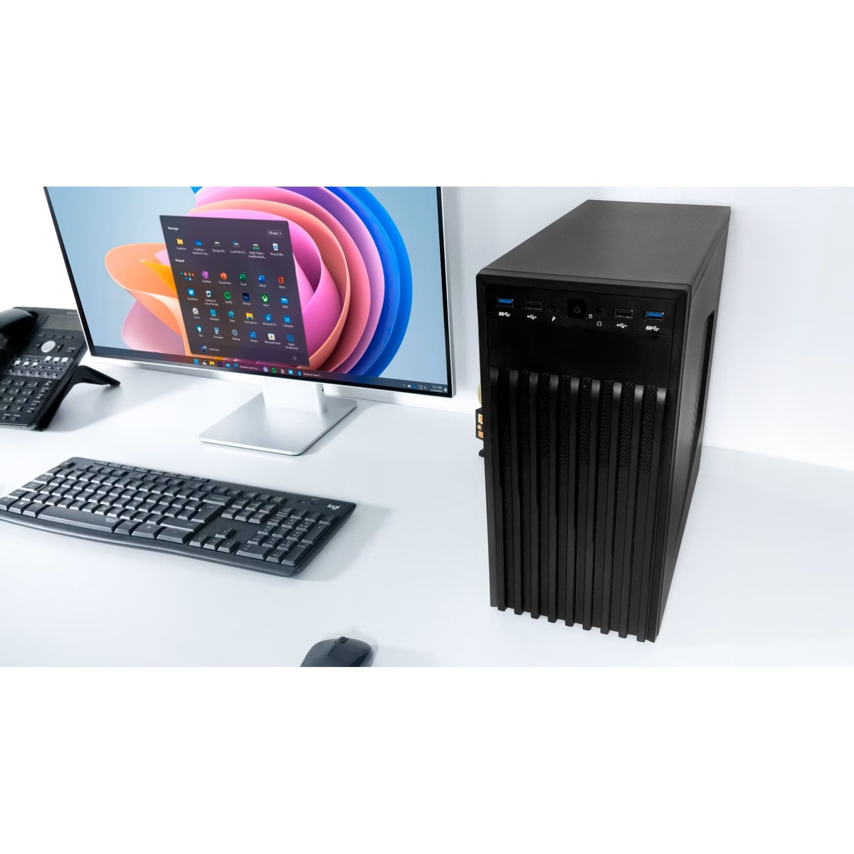 Una torre de computadora negra junto a un monitor con fondo de pantalla colorido.