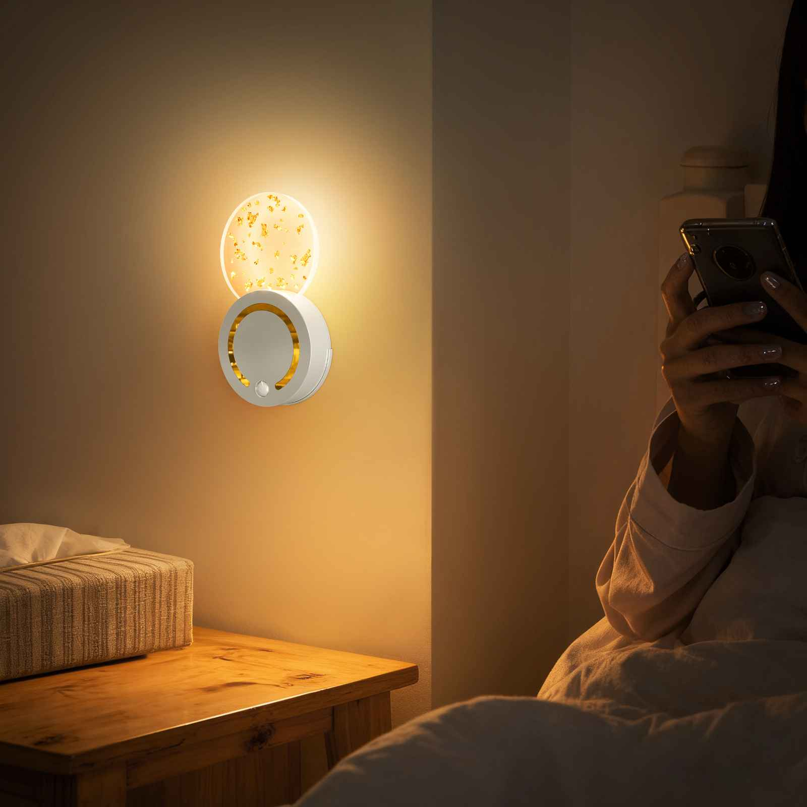 Ein Nachttisch mit einer Lampe und Taschentüchern neben einem Bett.
