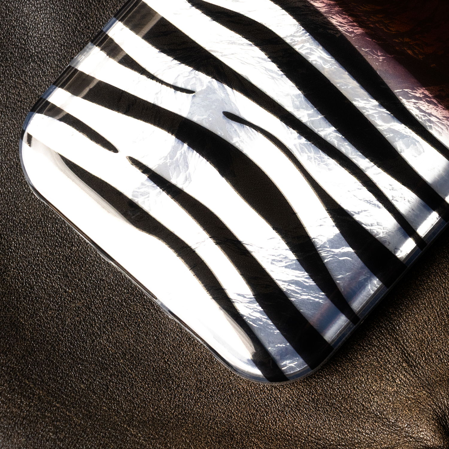 Zebra-Muster auf einer glänzenden Oberfläche, die auf dunkelbraunem Leder liegt.