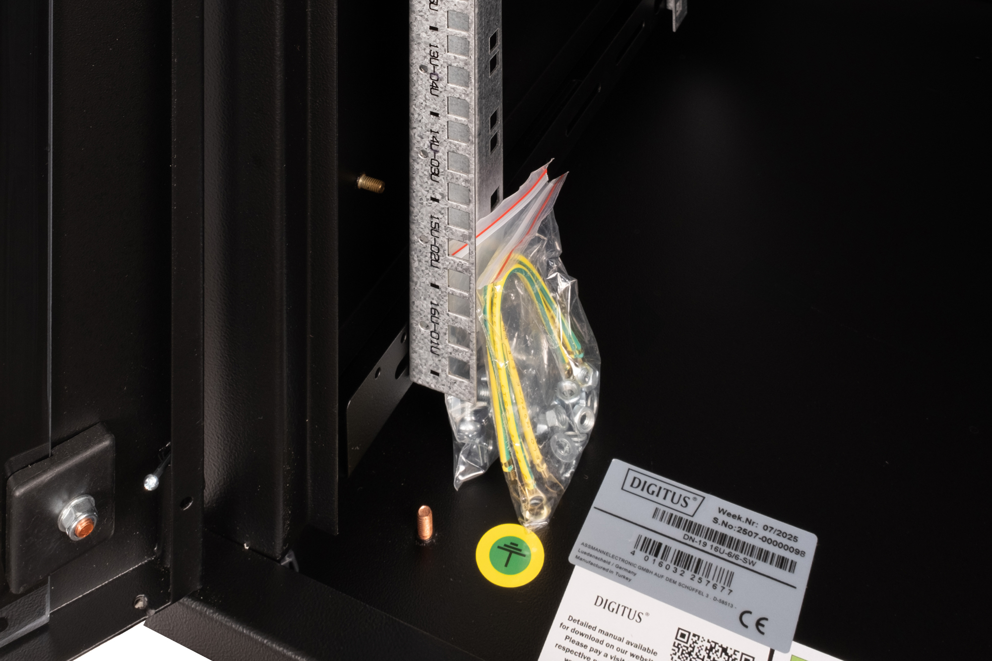 Schwarzes Rack mit Montagematerial, Erdungskabel und Anleitungsetikett.