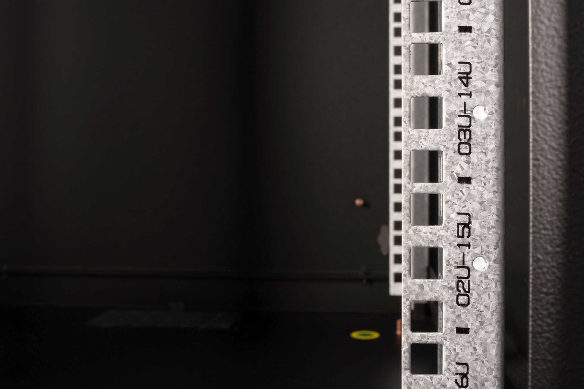 Detailaufnahme einer silbernen Rack-Schienenstruktur mit quadratischen Öffnungen und schwarzen Markierungen.