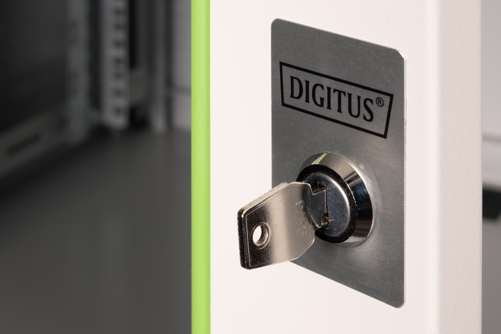 Una chiave argentata inserita in una serratura bianca per armadio con logo DIGITUS.