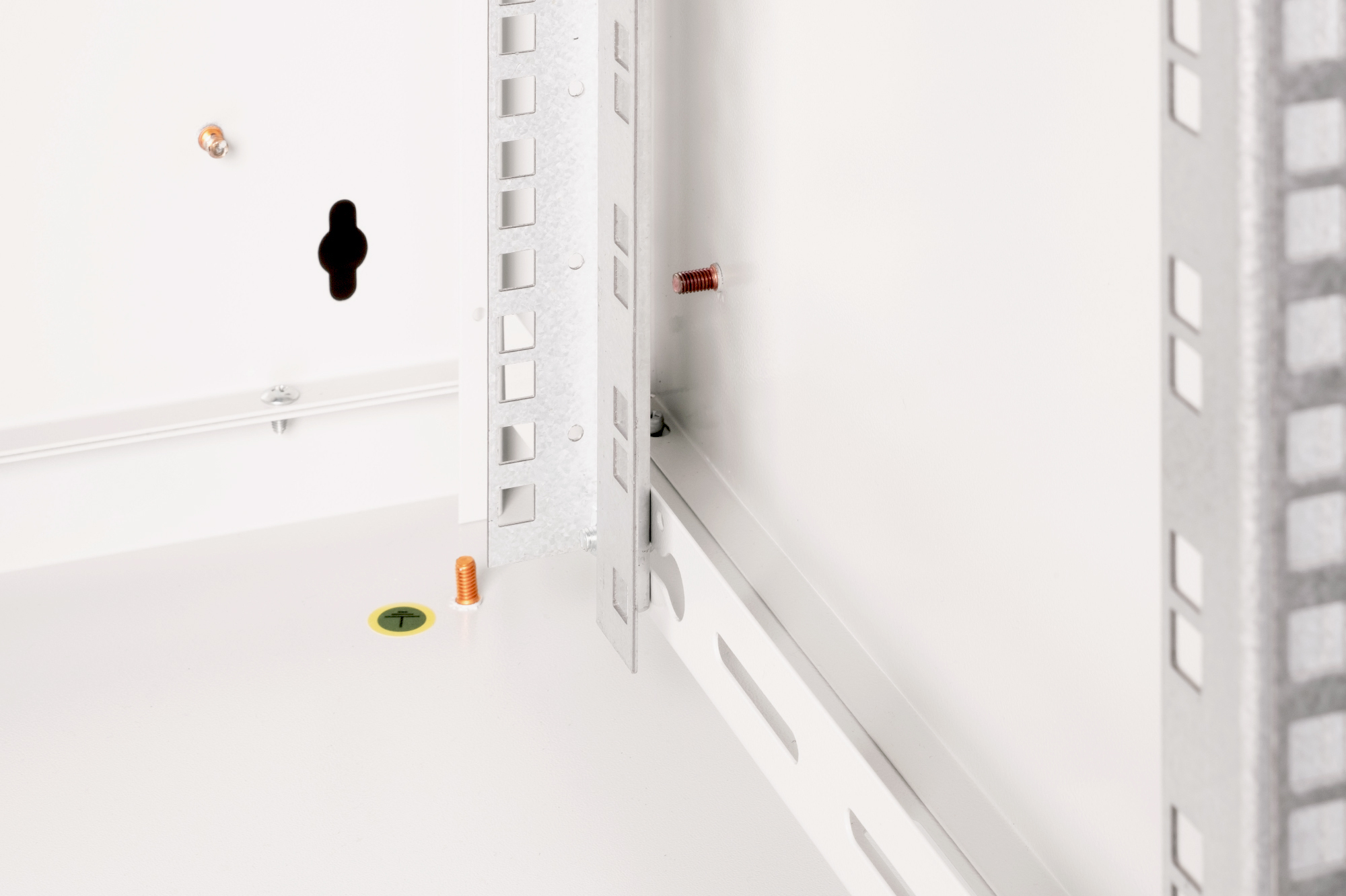 Detailansicht eines weißen Schranks mit Metallschienen und Schrauben.