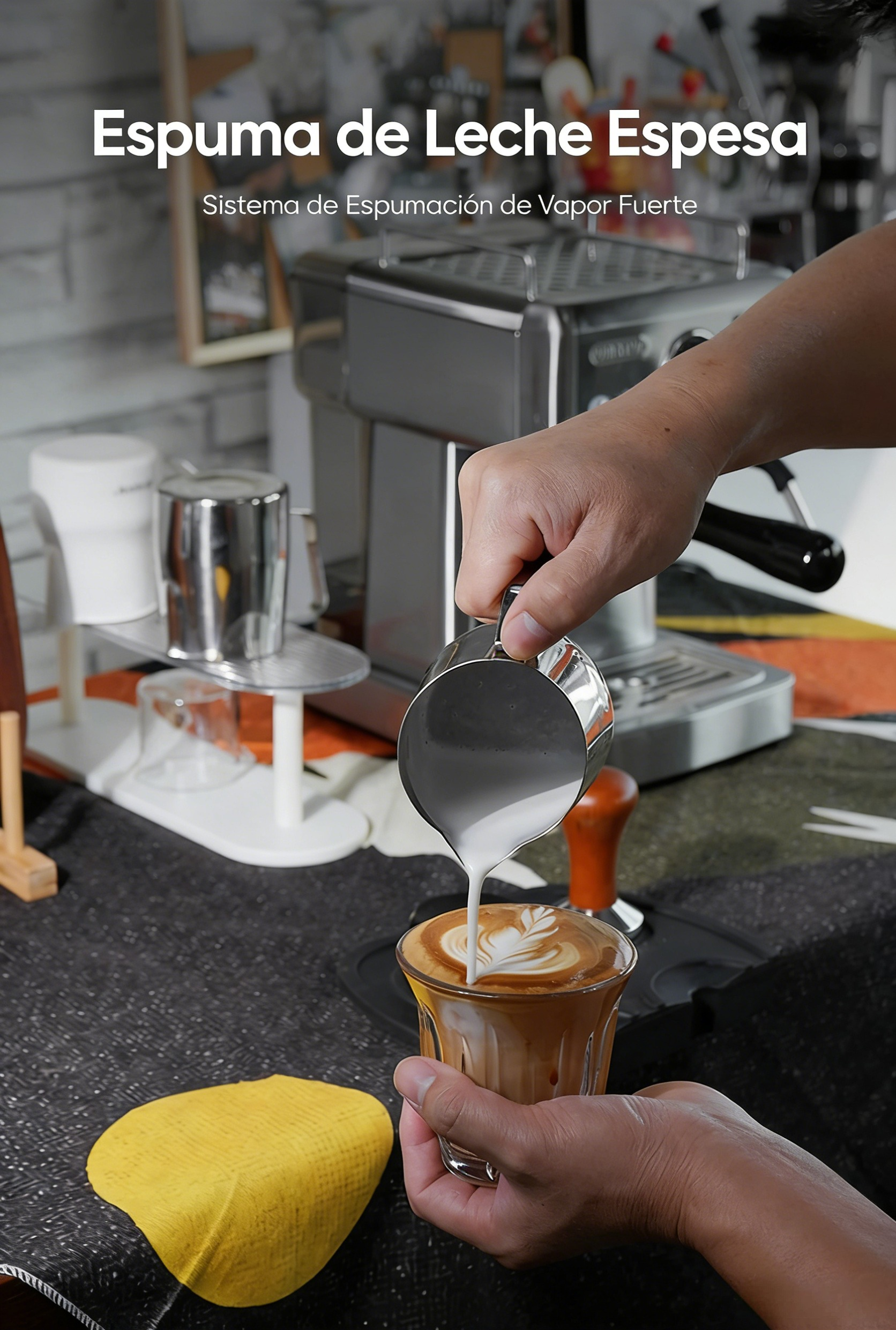 Una mano vierte leche espumada en café. Máquina de espresso al fondo.
