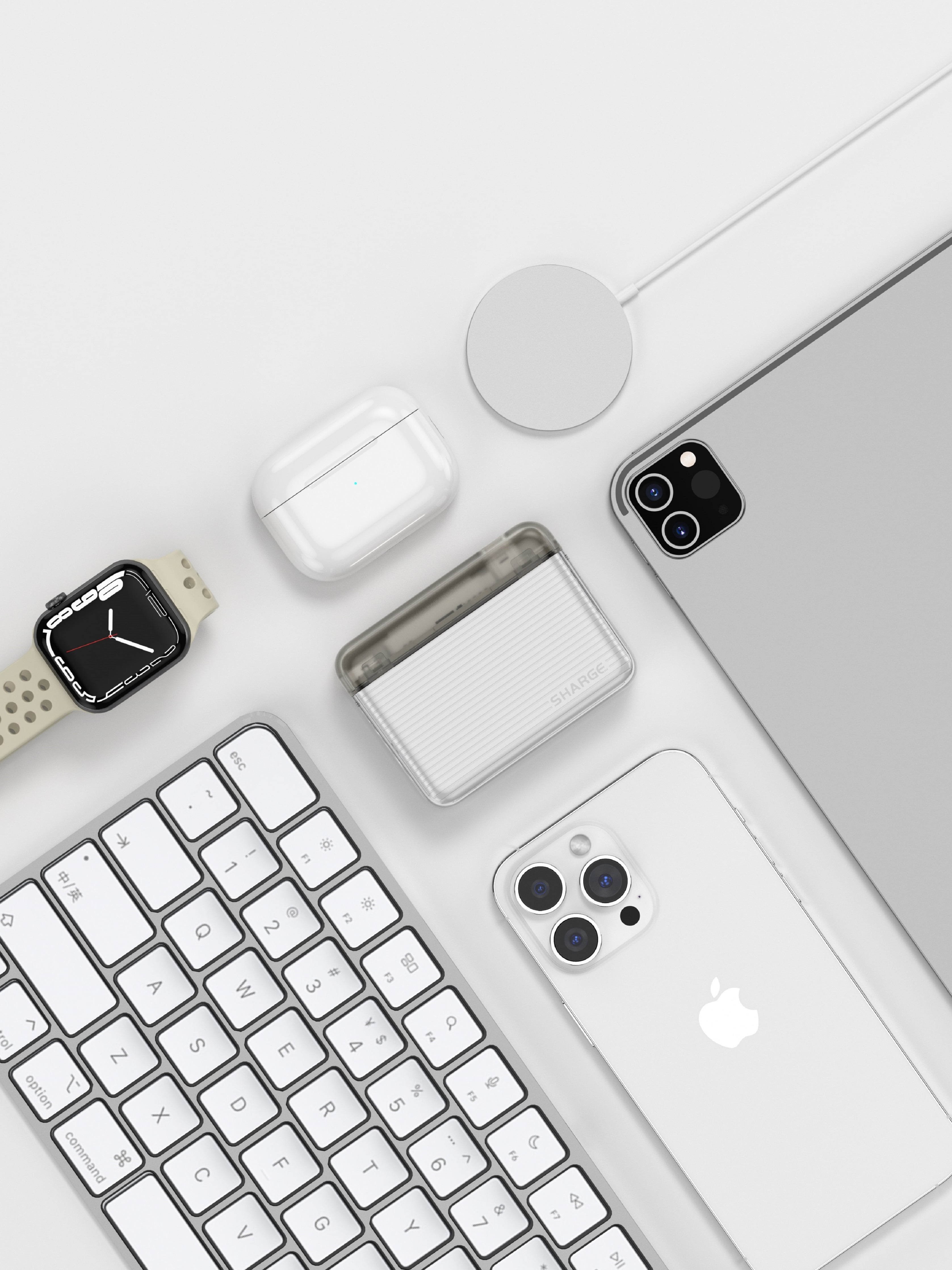 Une Apple Watch, un clavier, des AirPods, un chargeur et deux iPhones sur fond blanc.