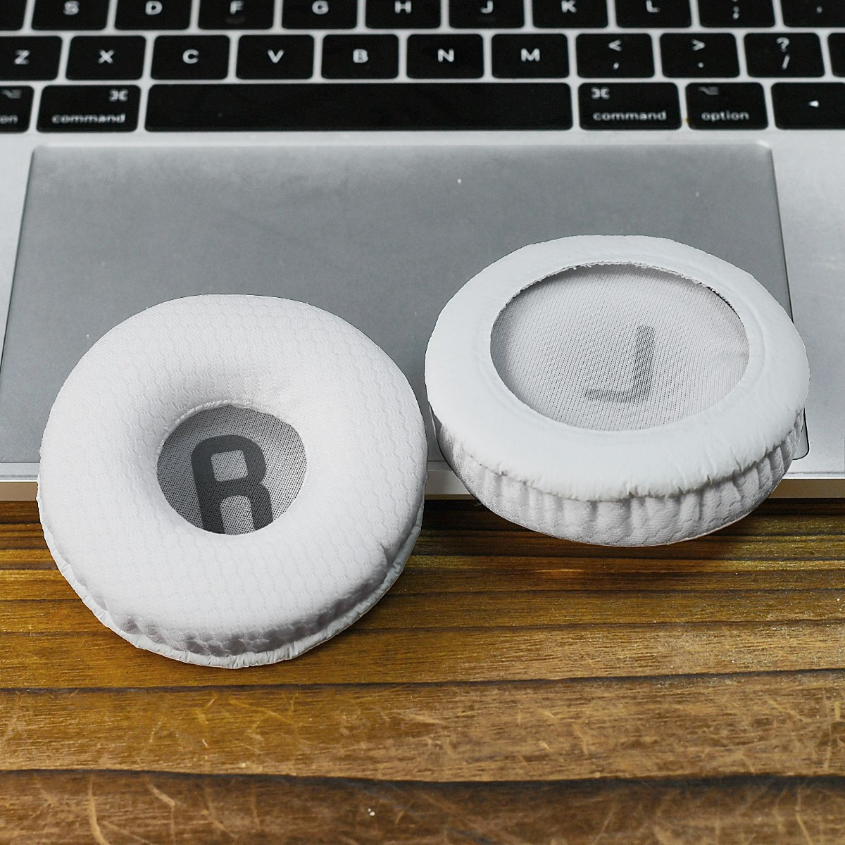 Dos almohadillas blancas para auriculares, una con R, la otra con L, sobre un teclado.
