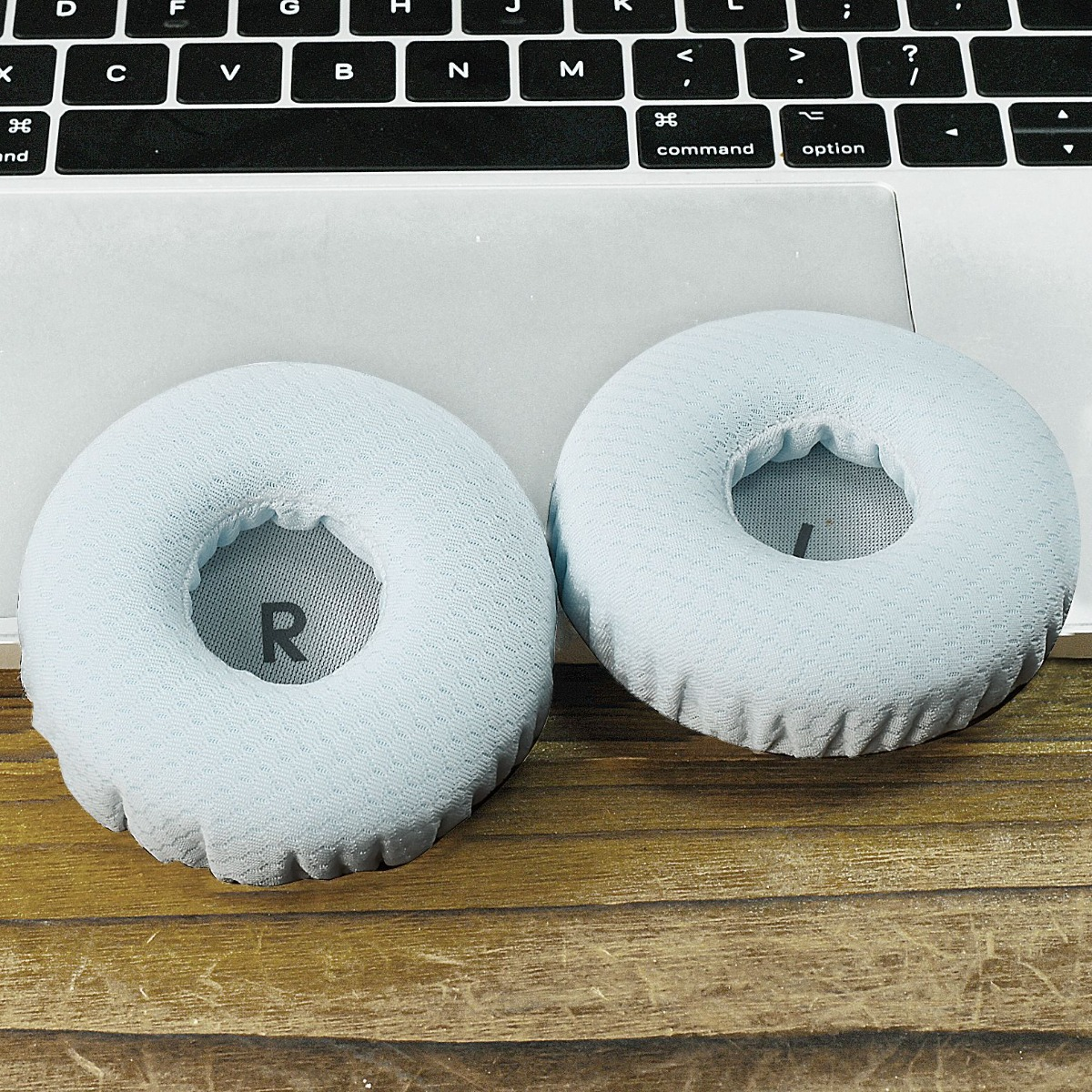Dos almohadillas azules claras descansan sobre un portátil y mesa de madera.