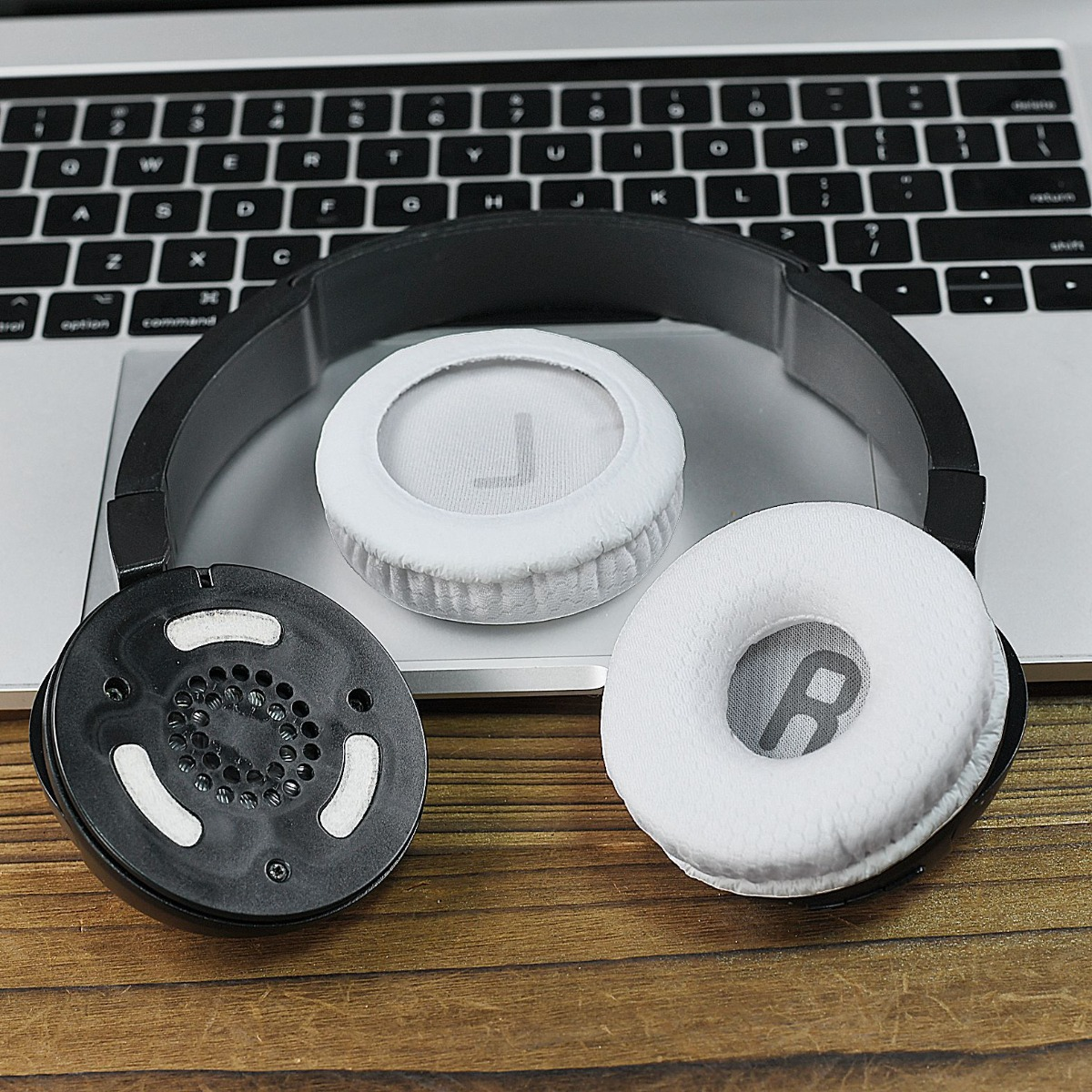 Auriculares negros con almohadillas blancas sobre un teclado.