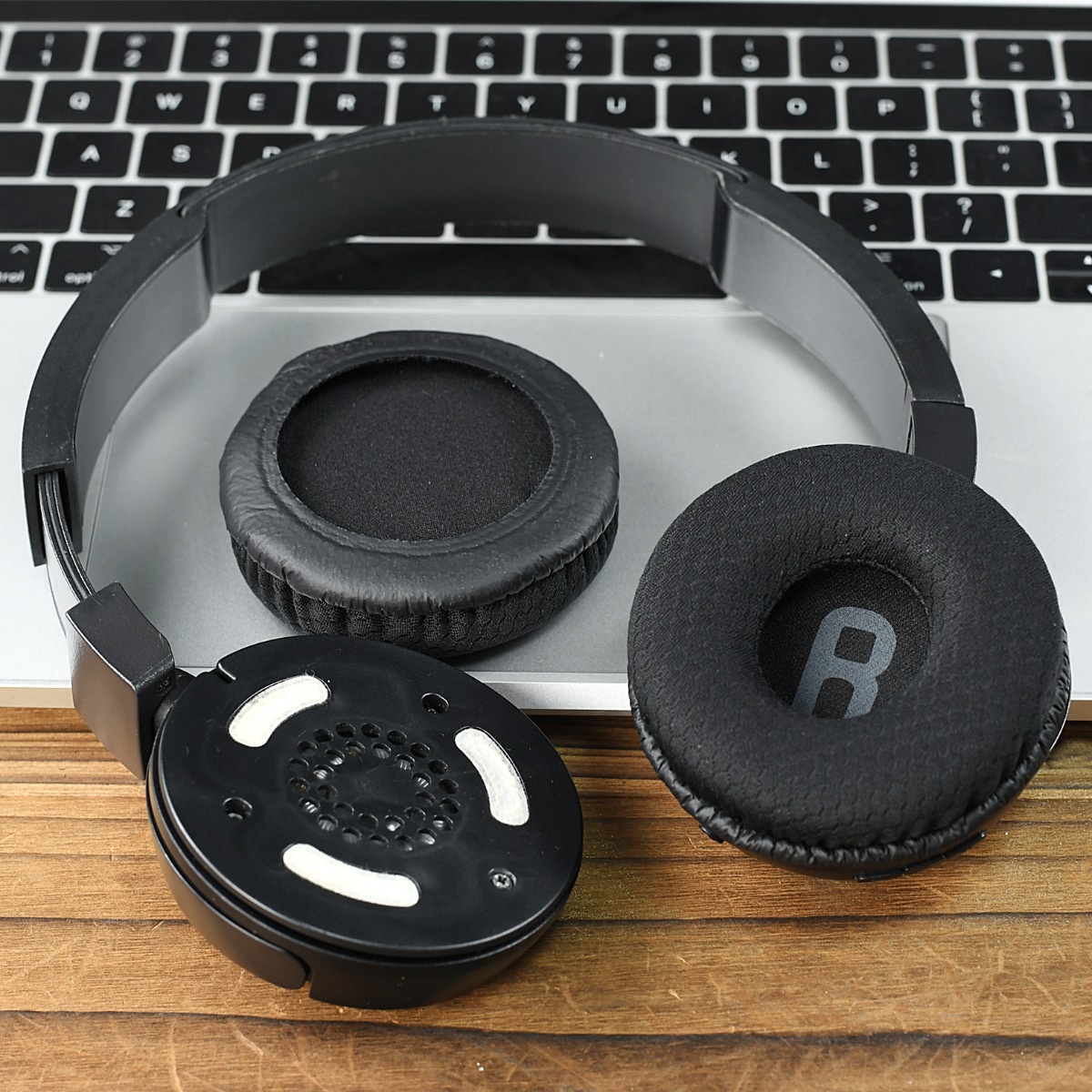 Auriculares negros descansan sobre un teclado y mesa de madera.