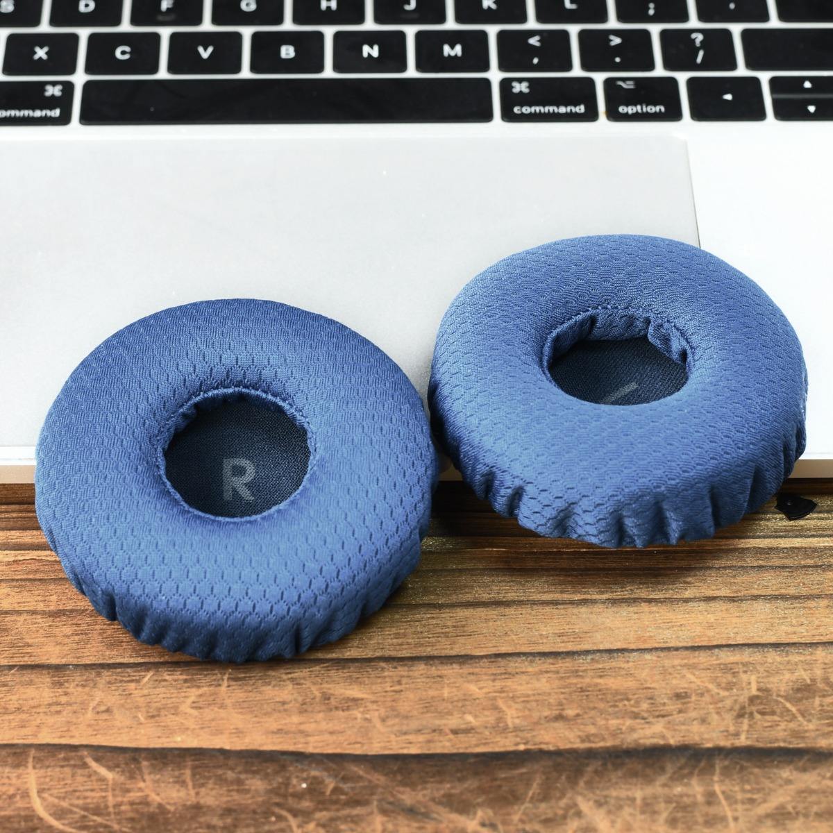 Dos almohadillas azules descansan sobre un portátil y una mesa de madera.