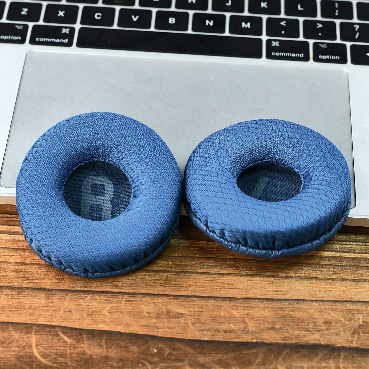 Dos almohadillas azules sobre un portátil, con superficie de madera detrás.