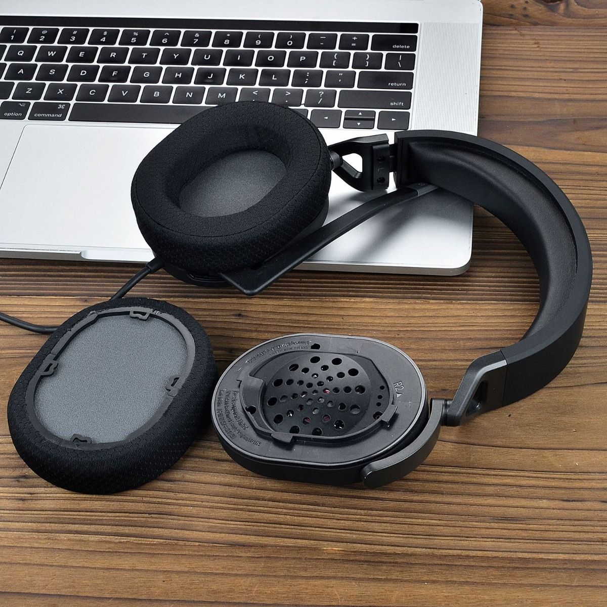 Auriculares negros con almohadillas quitadas sobre un teclado de portátil.