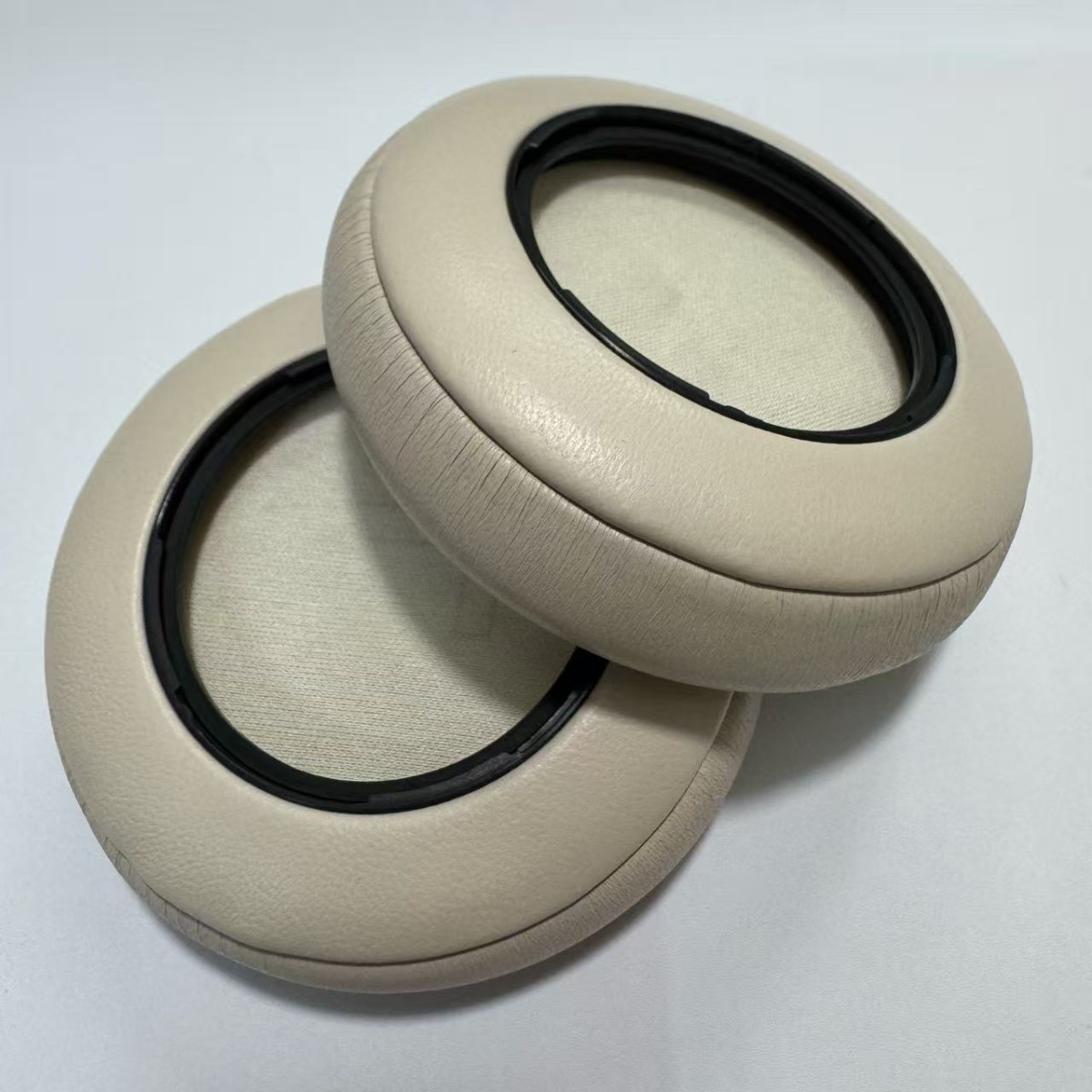 Dos almohadillas color crema con borde negro yacen una al lado de la otra.