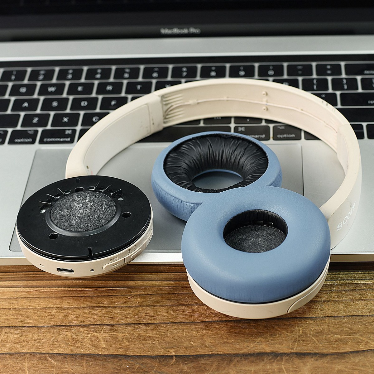 Una diadema de auriculares Sony blanca descansa sobre un teclado de portátil. Las almohadillas están separadas.