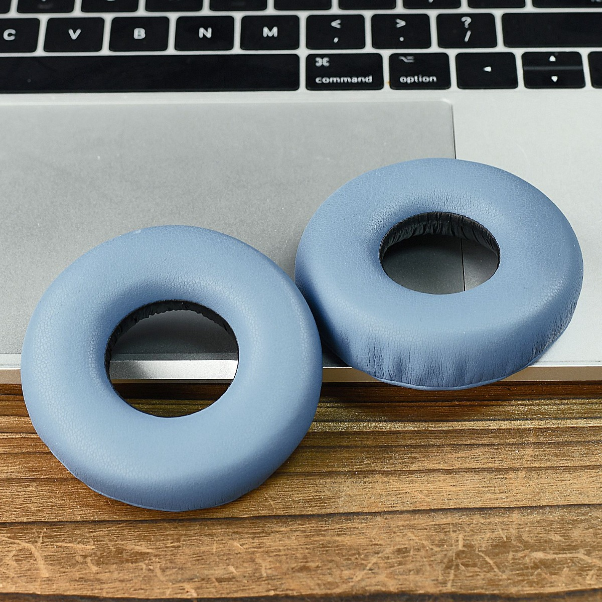 Dos almohadillas azules claras descansan sobre un teclado y mesa de madera.