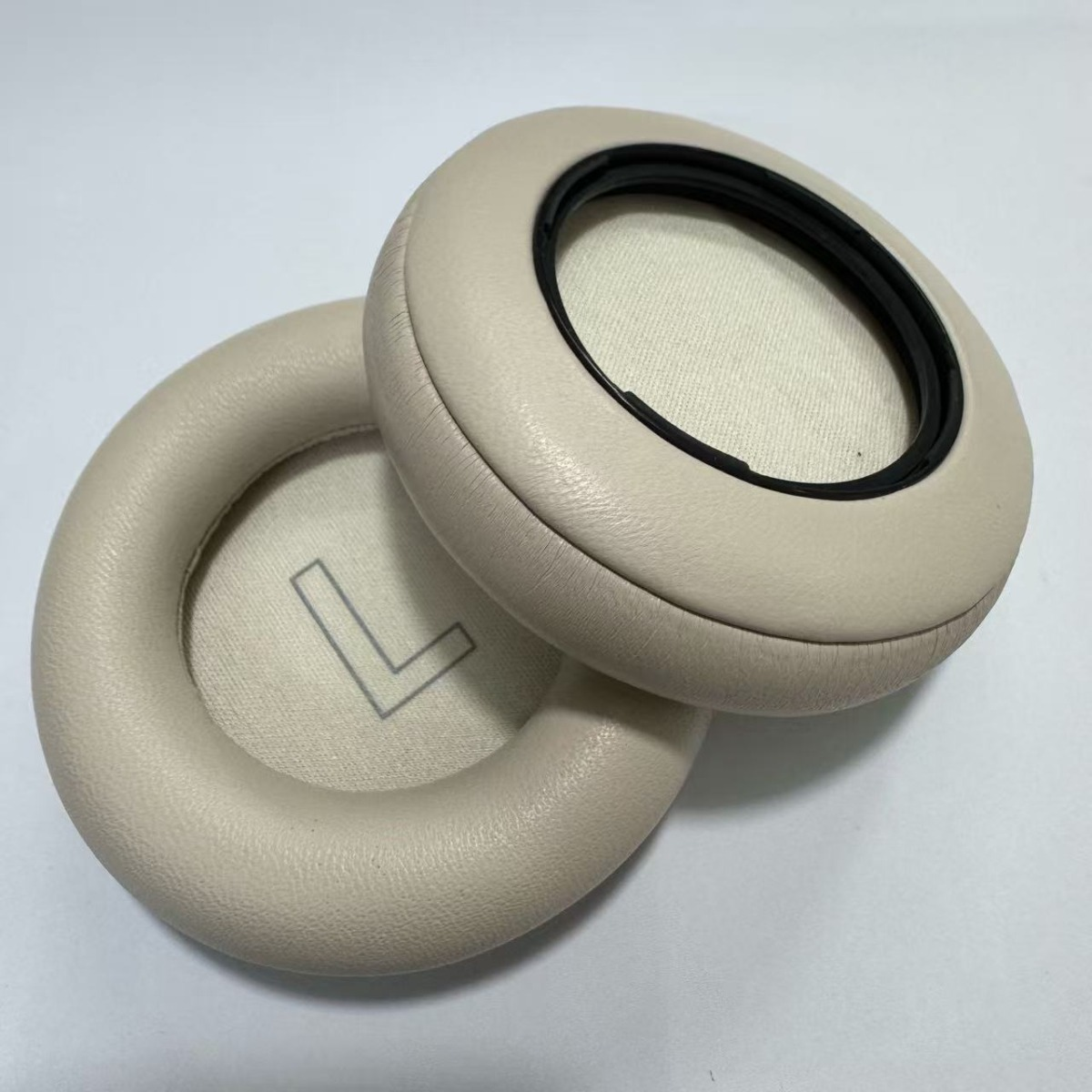 Dos almohadillas beige para auriculares están una al lado de la otra.