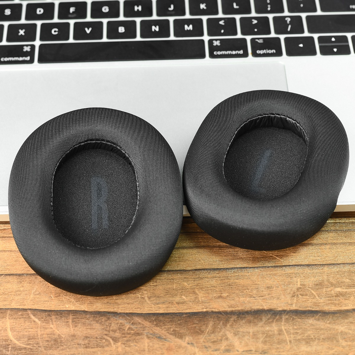 Dos almohadillas negras descansan sobre un teclado y mesa de madera.