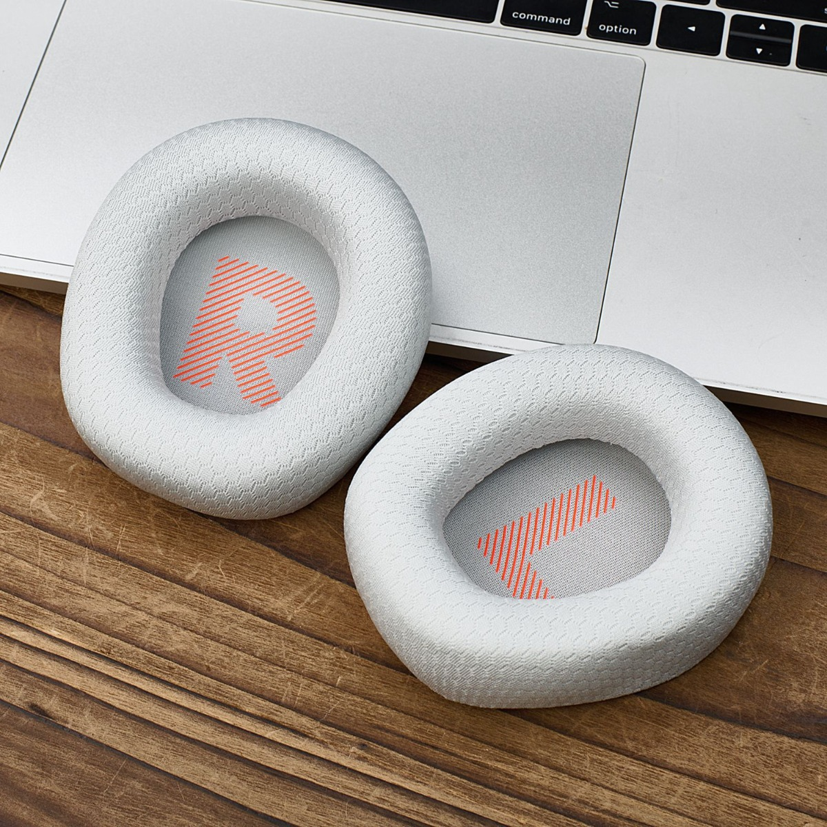 Dos almohadillas blancas con logo 'R' naranja sobre teclado y mesa madera.
