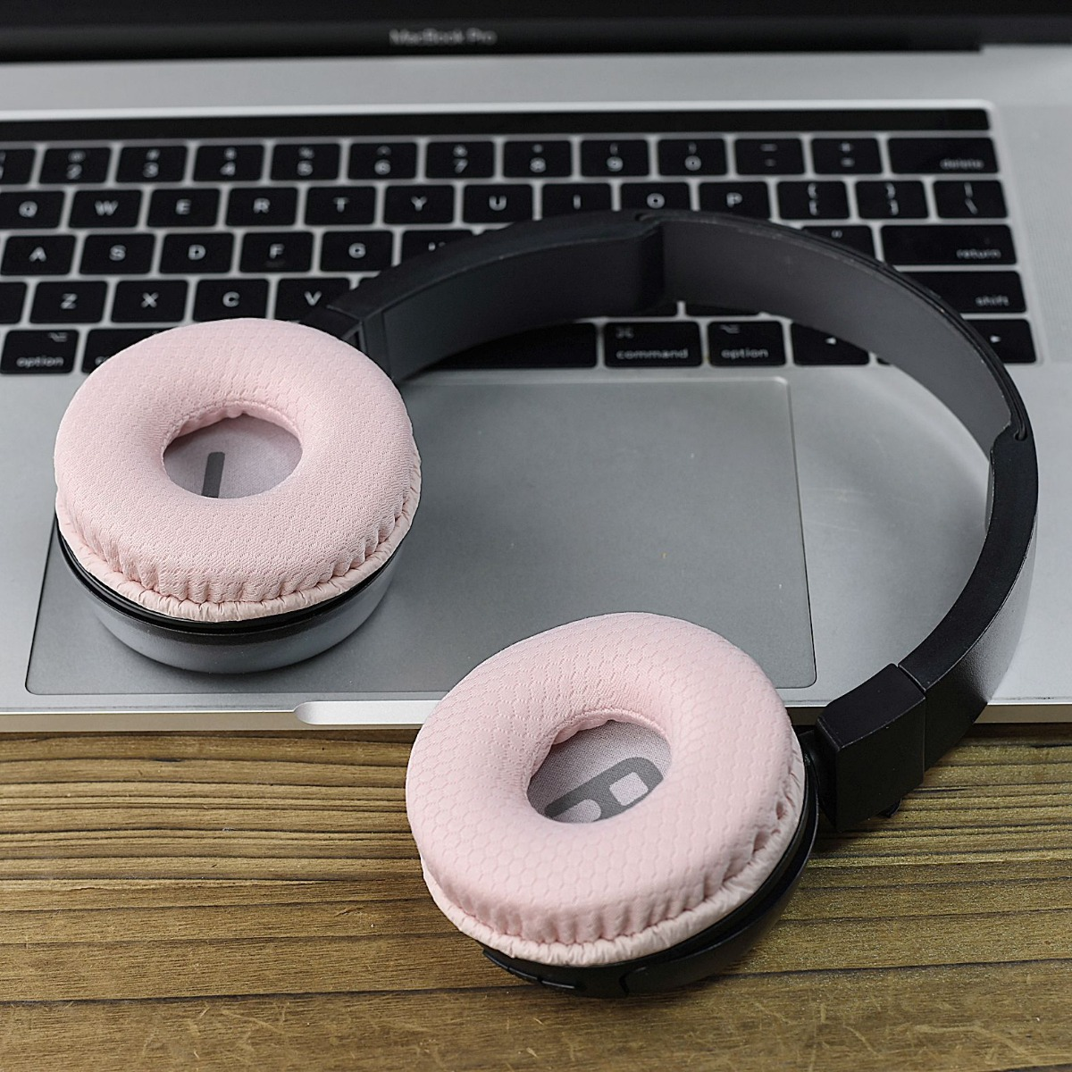 Unos auriculares rosas descansan sobre el teclado de un portátil.
