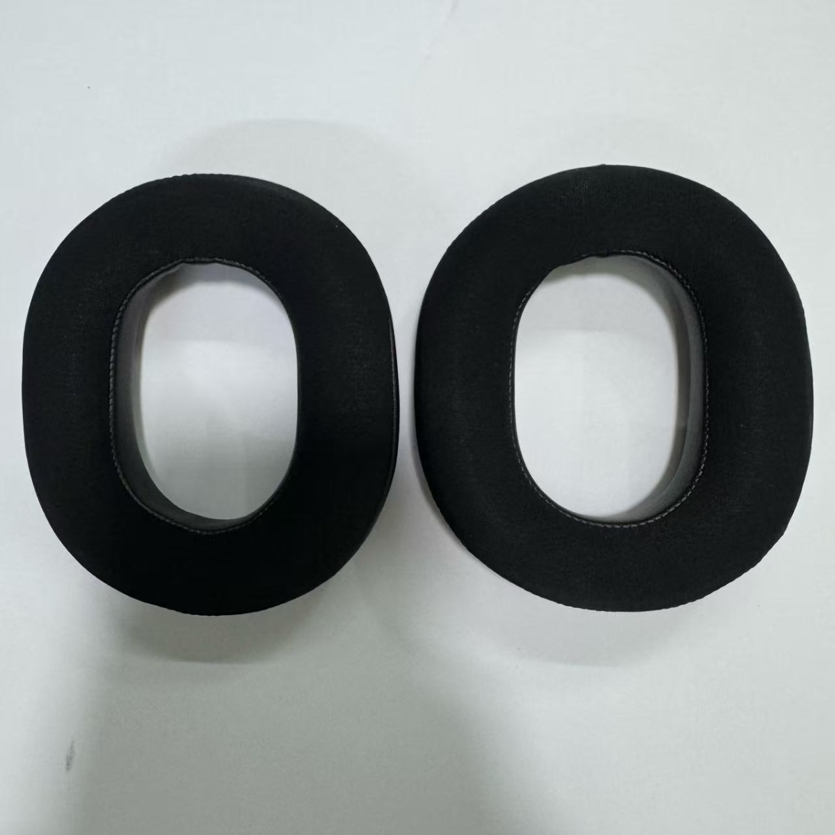 Dos almohadillas negras yacen una al lado de la otra sobre fondo blanco.