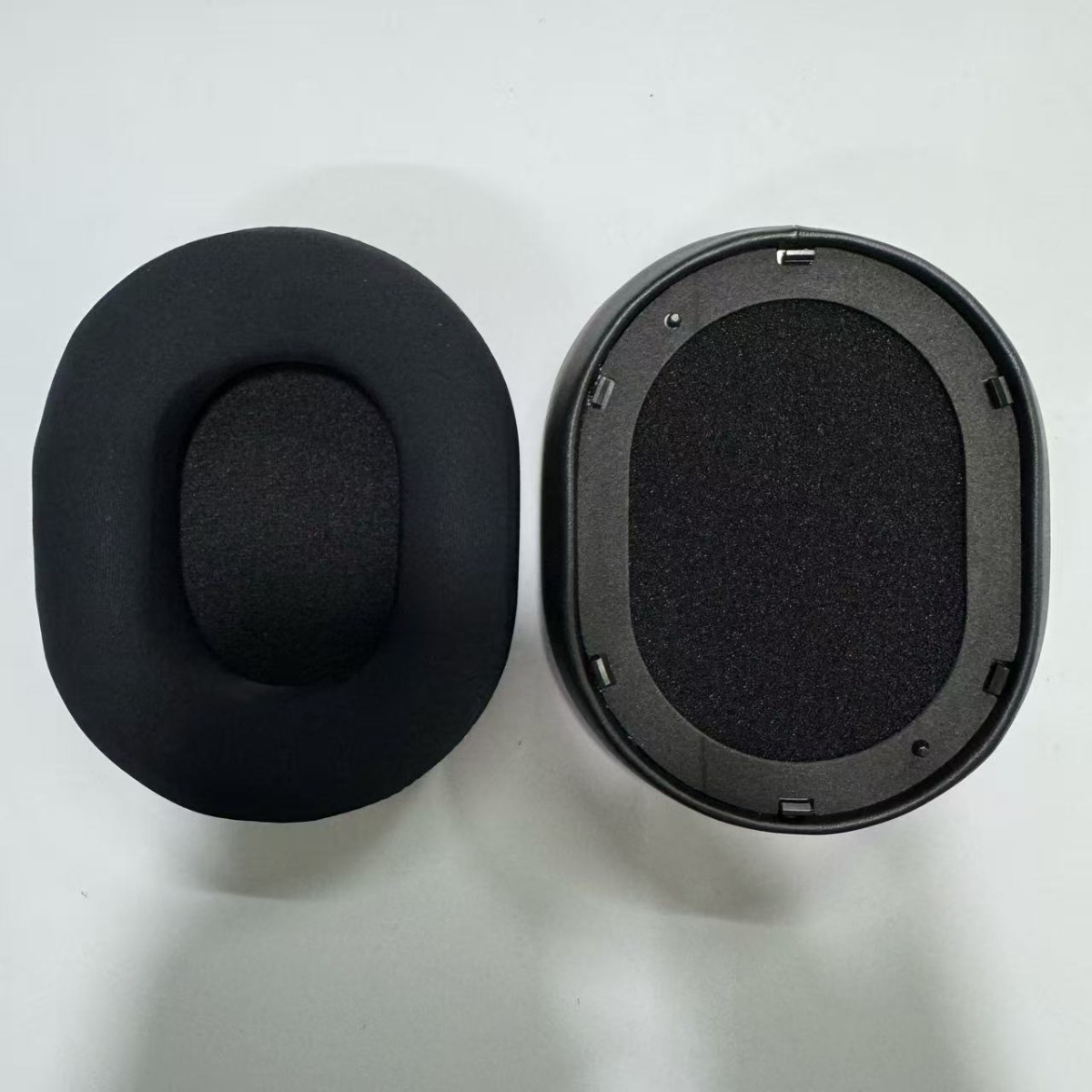 Dos almohadillas negras para auriculares, una cubierta de tela, otra con marco.