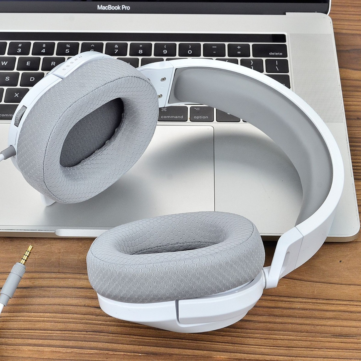 Auriculares blancos con almohadillas grises sobre un teclado.