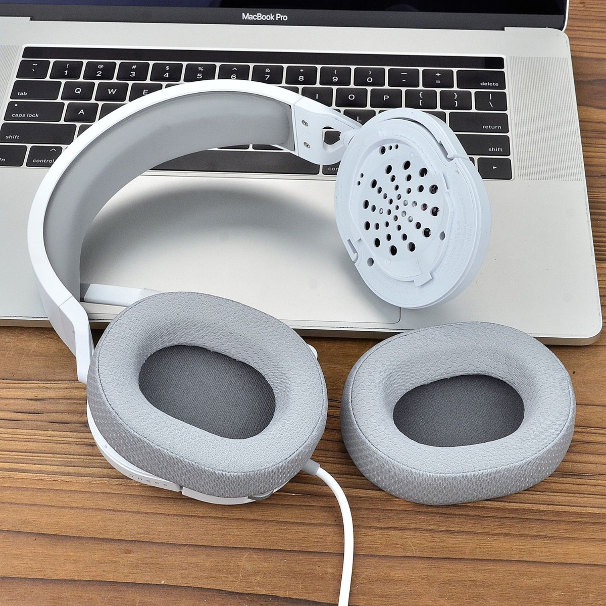 Auriculares blancos con almohadillas grises sobre un teclado.