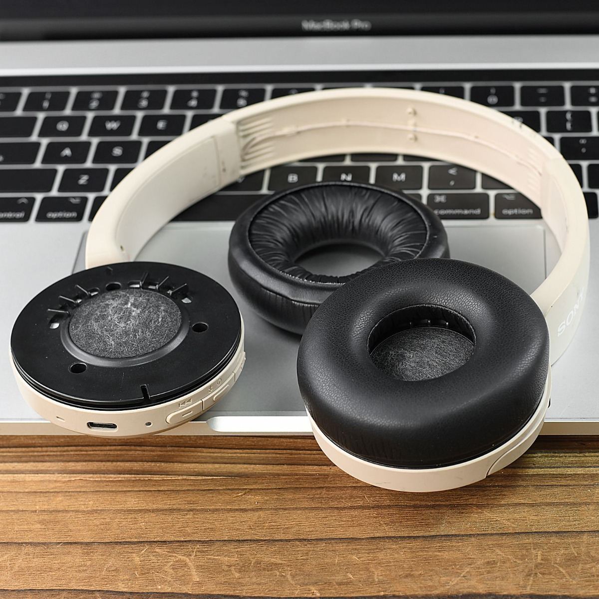 Un audífono beige desmontado yace sobre un teclado de portátil.