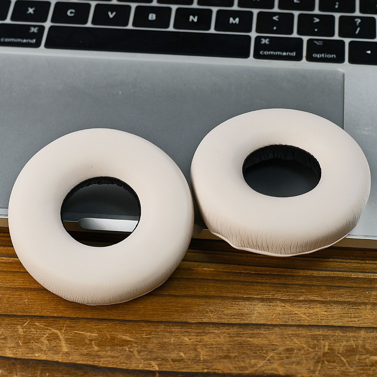 Dos almohadillas color crema descansan sobre un teclado y mesa de madera.