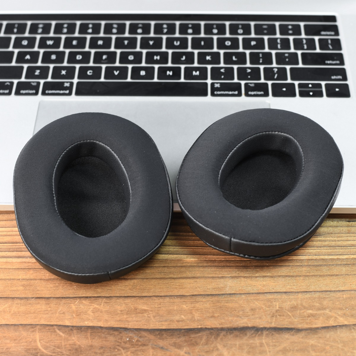Dos almohadillas negras descansan sobre un teclado y una mesa de madera.