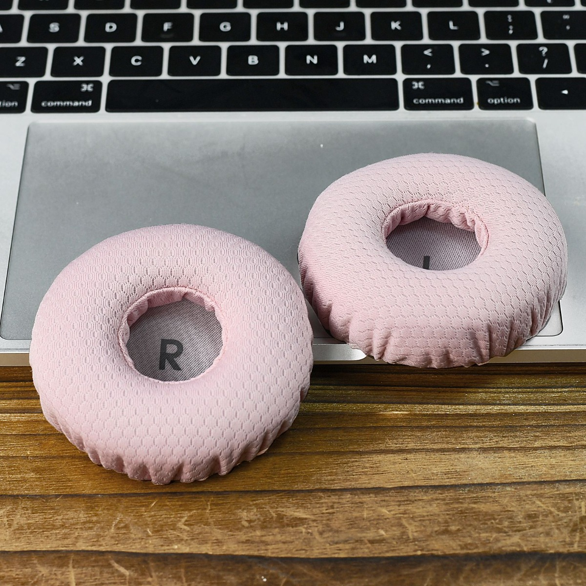 Dos almohadillas rosas descansan sobre un teclado y un portátil.